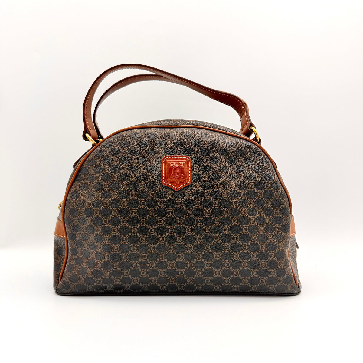 Front view of the Celine Triomphe Macadam Dome Handbag in brown, featuring the signature monogram canvas and tan leather details.