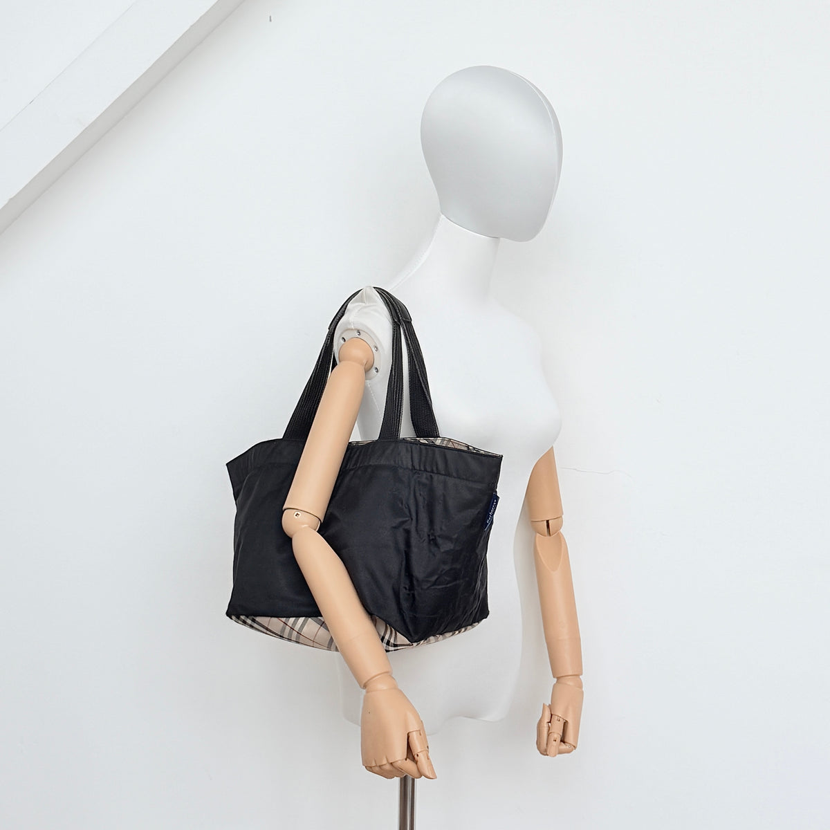 Burberry Blue Label Nova Check tote bag in black nylon with beige checked base and webbed handles, shown on white background.