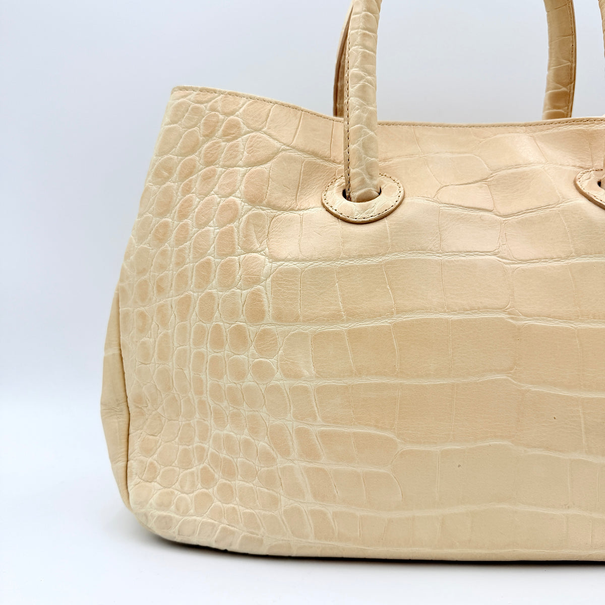Furla beige croc-embossed leather handbag with double handles and silver-tone logo medallion, photographed on a white background.