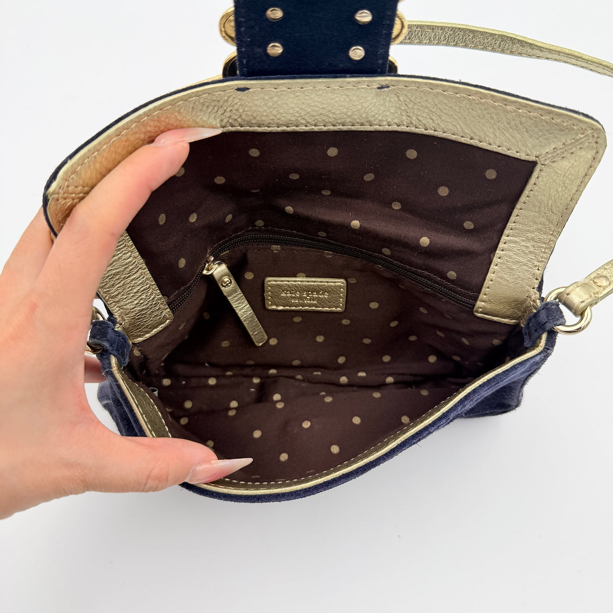 Navy blue suede Kate Spade baguette bag with floral gold hardware and gold-tone shoulder strap.