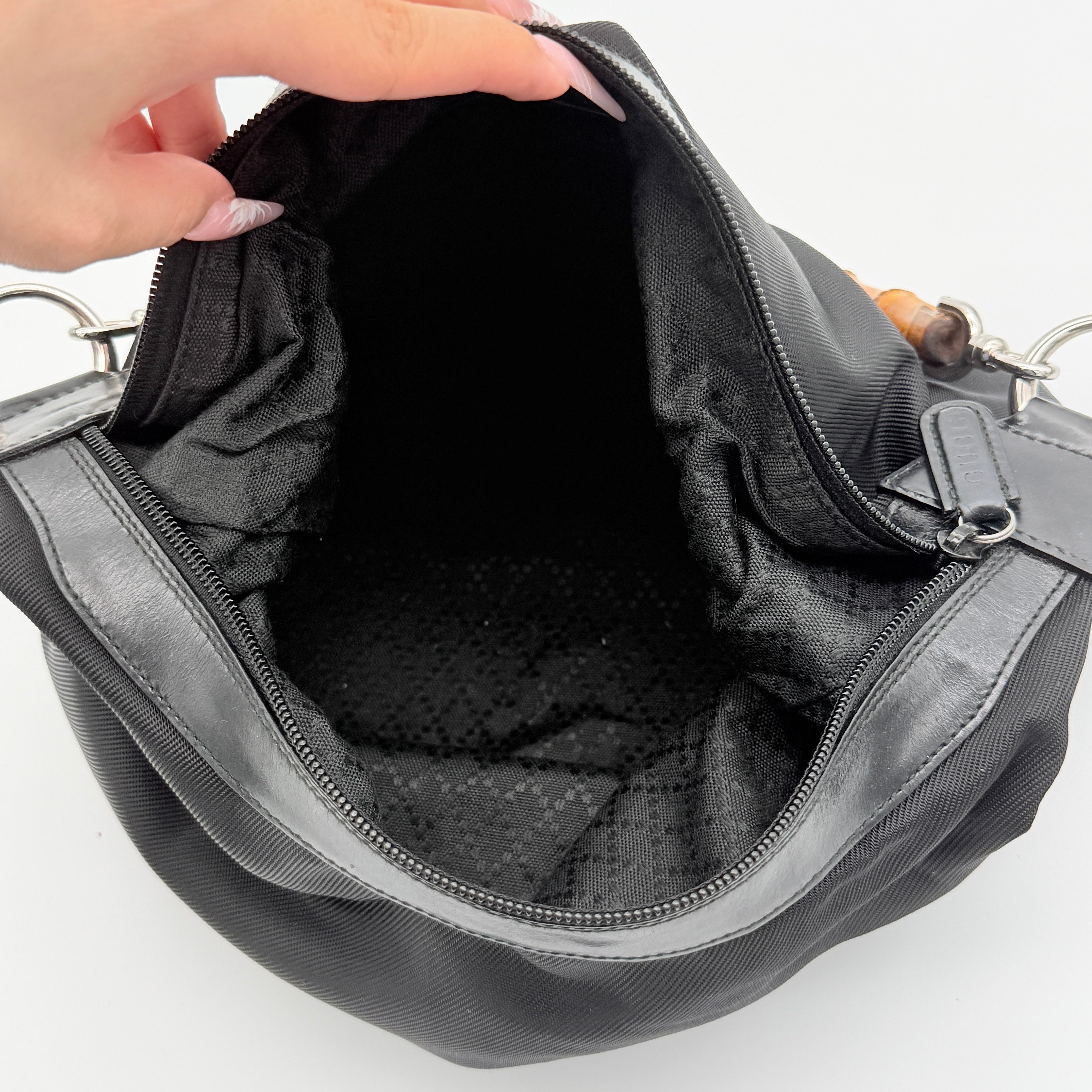 Gucci black nylon shoulder bag with bamboo handle and leather trim, photographed against a white background.