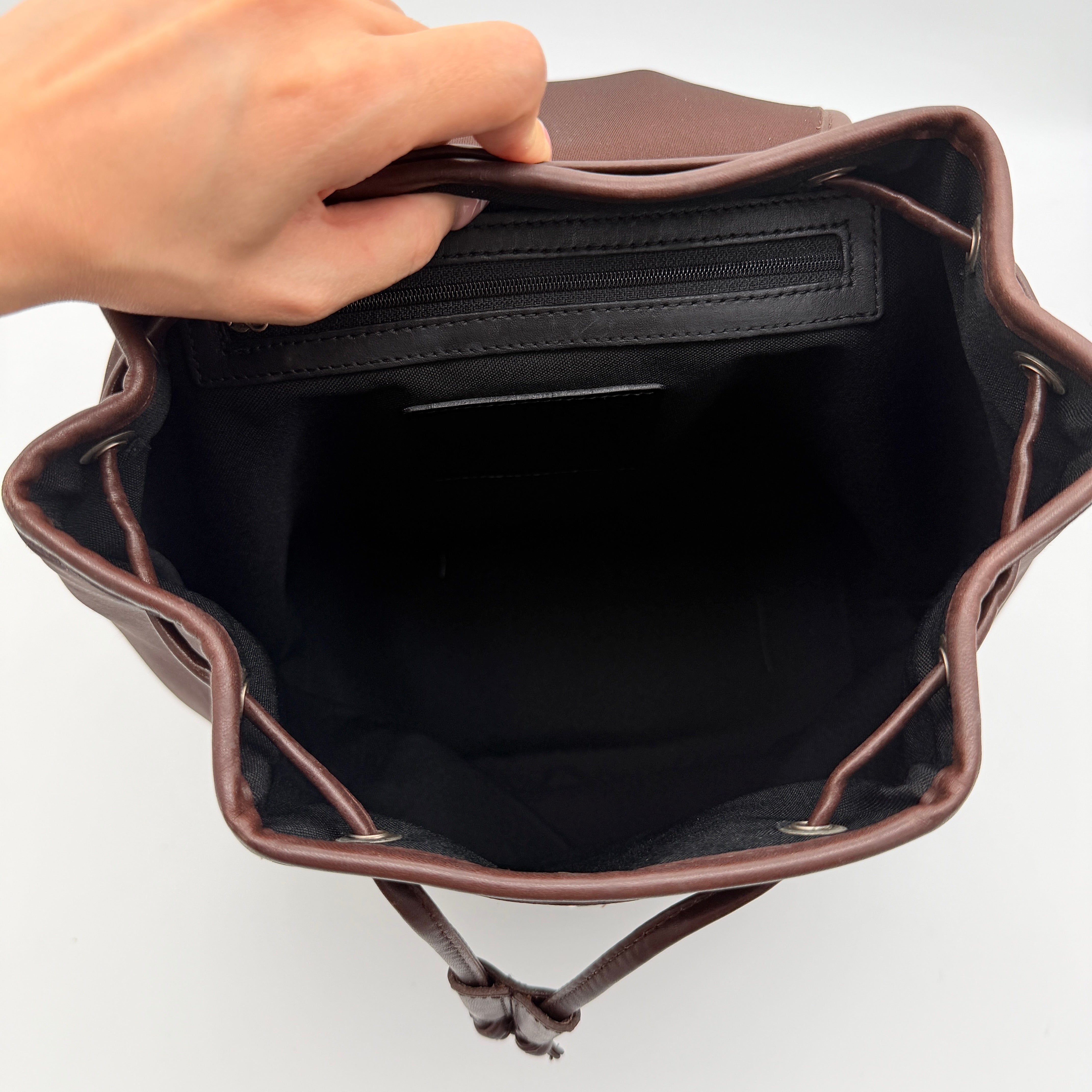 Coach brown neoprene drawstring backpack with leather trim, silver-tone hardware, and adjustable straps shown against a white background.