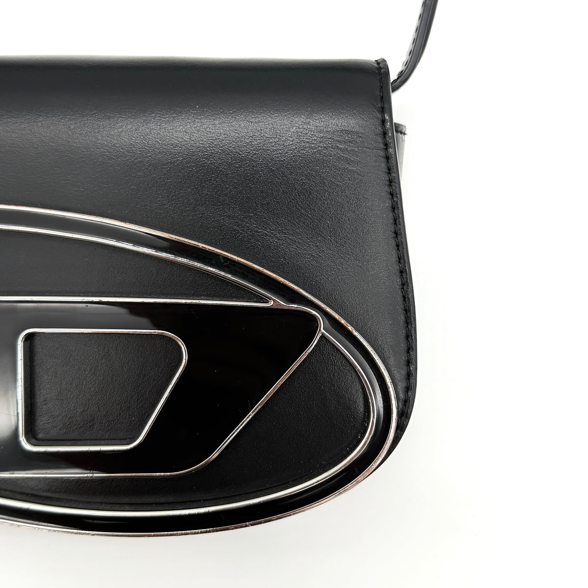 Diesel 1DR Shoulder Bag in black leather with a bold silver and black D logo plaque on the front flap.