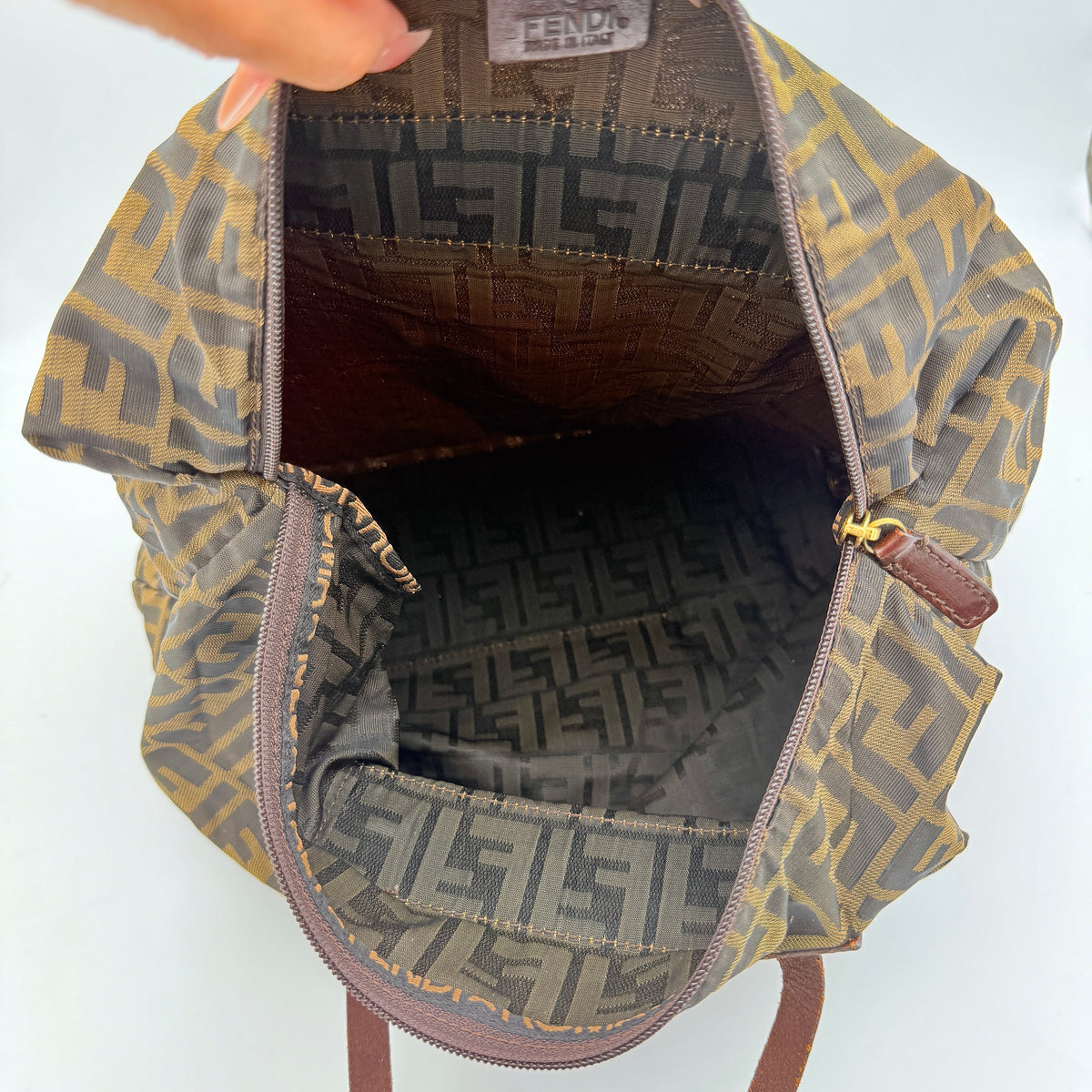 Fendi FF Zucca foldable tote bag in brown canvas with leather top handles and all-over monogram, shown standing upright.