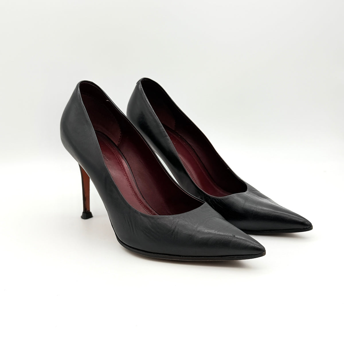 A pair of black leather Celine stiletto heels with pointed toes and burgundy insoles, shown in a softly lit studio setting.