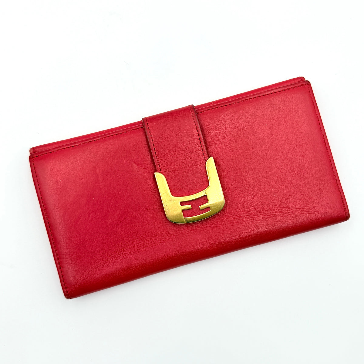 Fendi FF Logo Buckle Flap Continental Wallet in red leather with gold hardware, displayed closed on a white background.