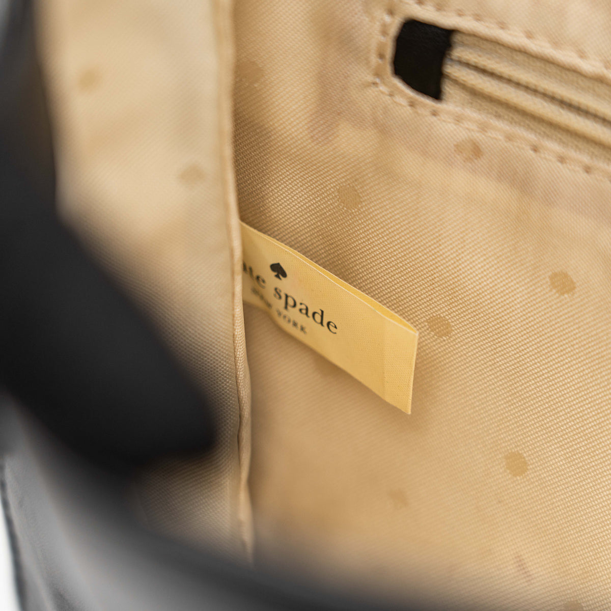 Kate Spade New York black leather shoulder bag with gold chain strap and bow detail, displayed against a white background.