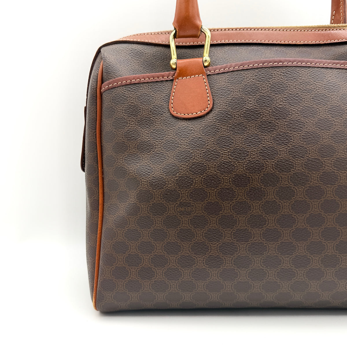 Celine Triomphe Macadam Boston Bag in brown coated canvas with tan leather handles and gold hardware on a white background.