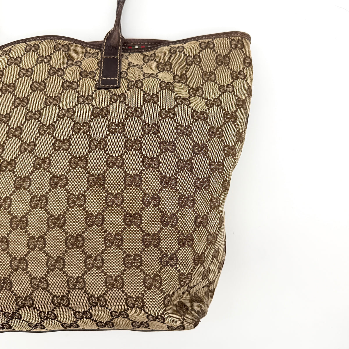 Gucci GG Monogram New Britt Tote Bag in beige and brown canvas with leather trim and gold-tone logo, presented against a white backdrop.