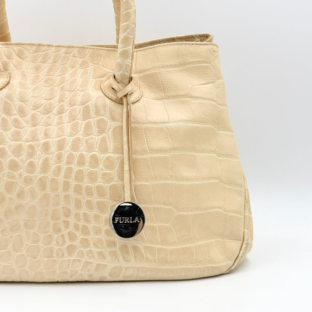 Furla beige croc-embossed leather handbag with double handles and silver-tone logo medallion, photographed on a white background.
