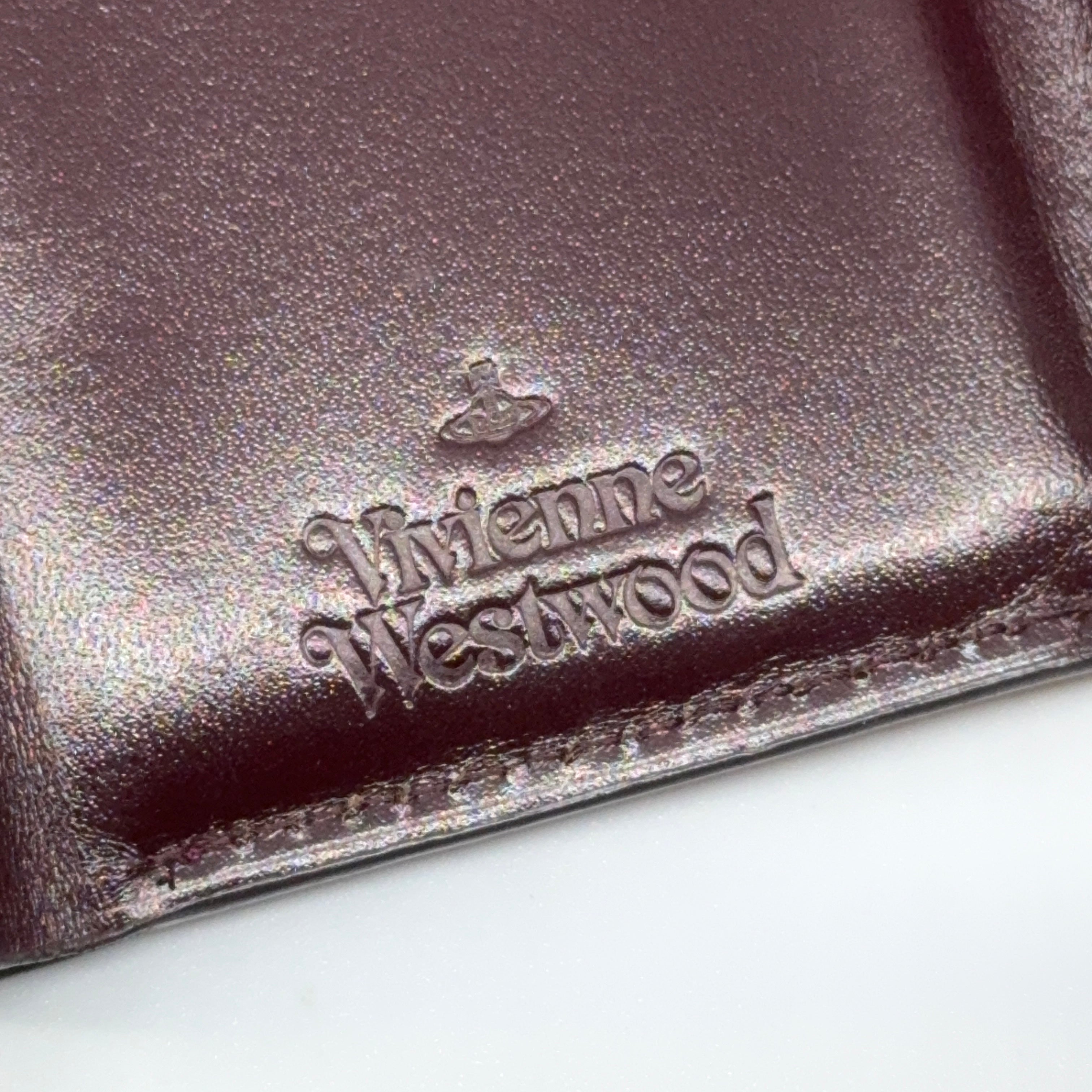 Vivienne Westwood Signature Orb Wallet in glossy purple leather with silver orb emblem on the front flap.