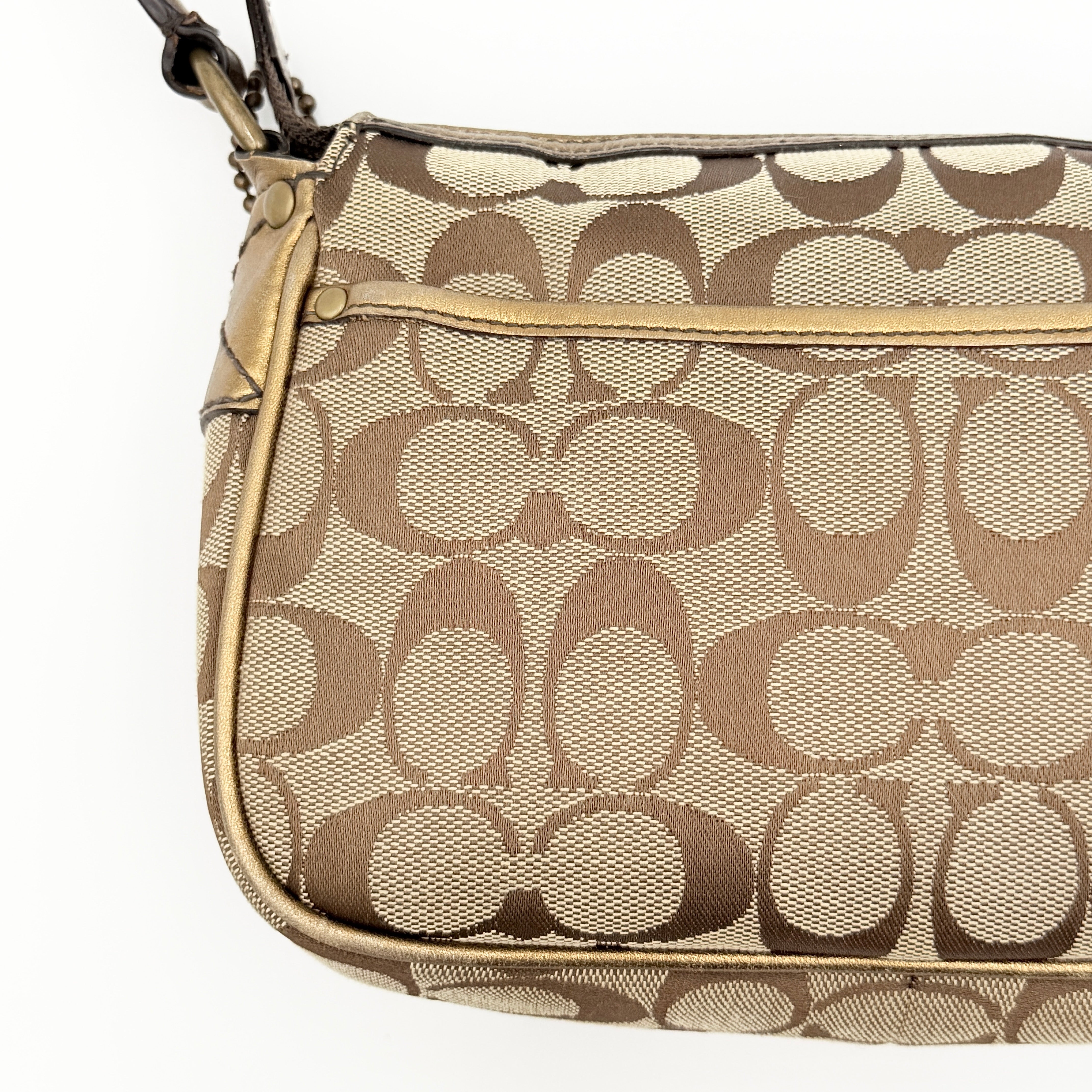Coach Signature shoulder bag in beige jacquard with gold leather front flap, showcased on a plain background.