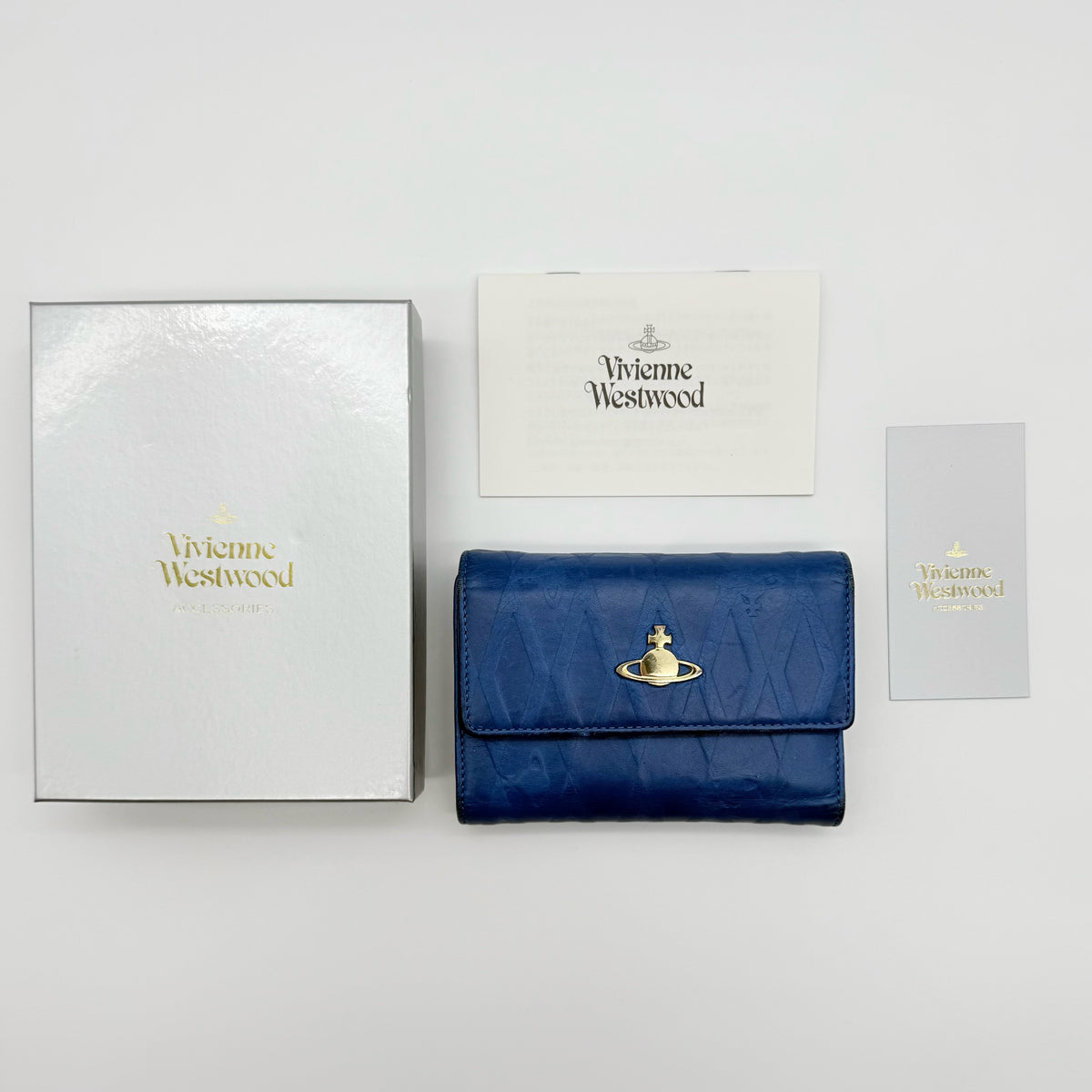 Vivienne Westwood blue leather trifold wallet with gold Orb emblem, shown with original box and documents.