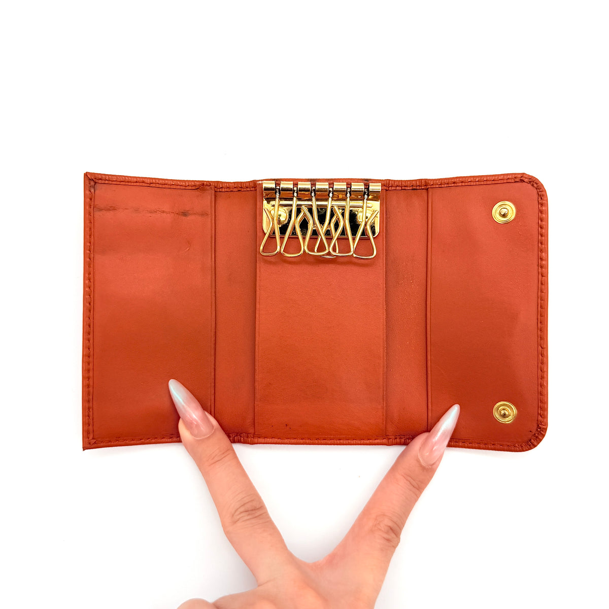 Prada Saffiano leather key case in orange with gold-toned hardware, Prada logo, and authenticity card displayed.