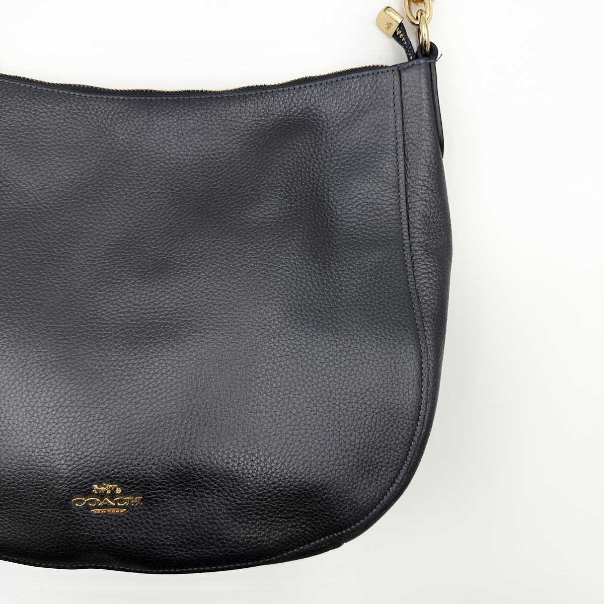 Coach Elle Hobo bag in navy blue pebbled leather with gold hardware and a detachable strap, styled on a white background.