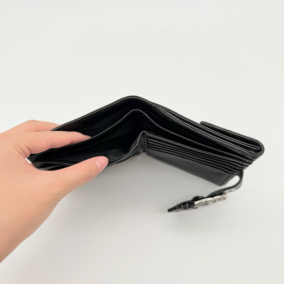 Coach black Soho Bifold Wallet with signature silver buckle and contrast stitching, shown closed against a white background.