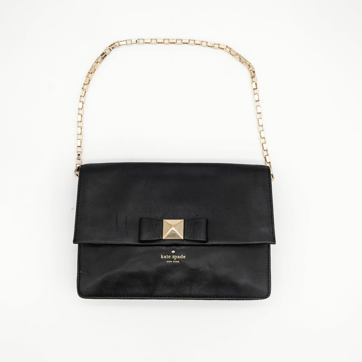 Kate Spade New York black leather shoulder bag with gold chain strap and bow detail, displayed against a white background.