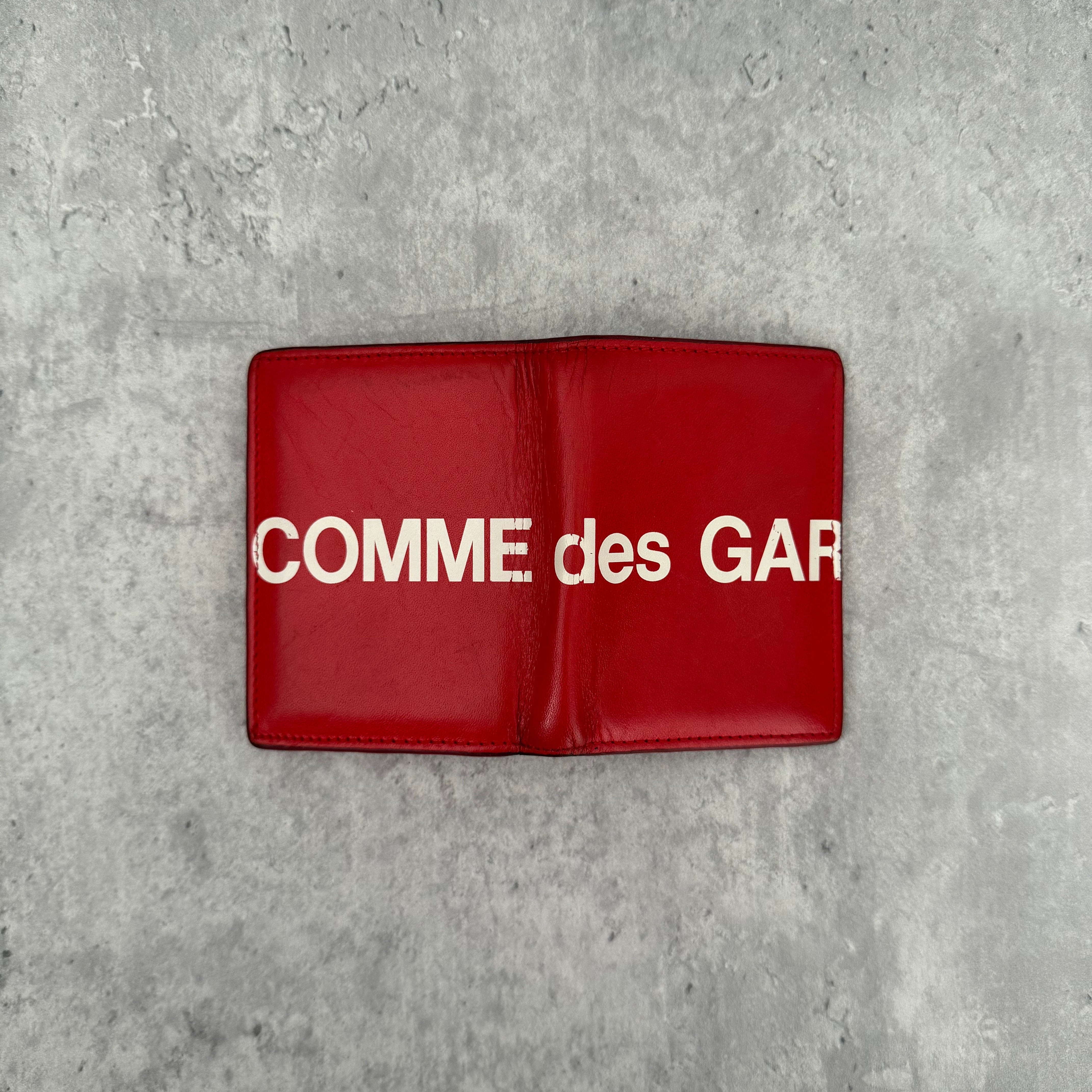 COMME des GARÇONS Huge Logo Red Leather Wallet with oversized white print and multiple card slots in a bi-fold design.