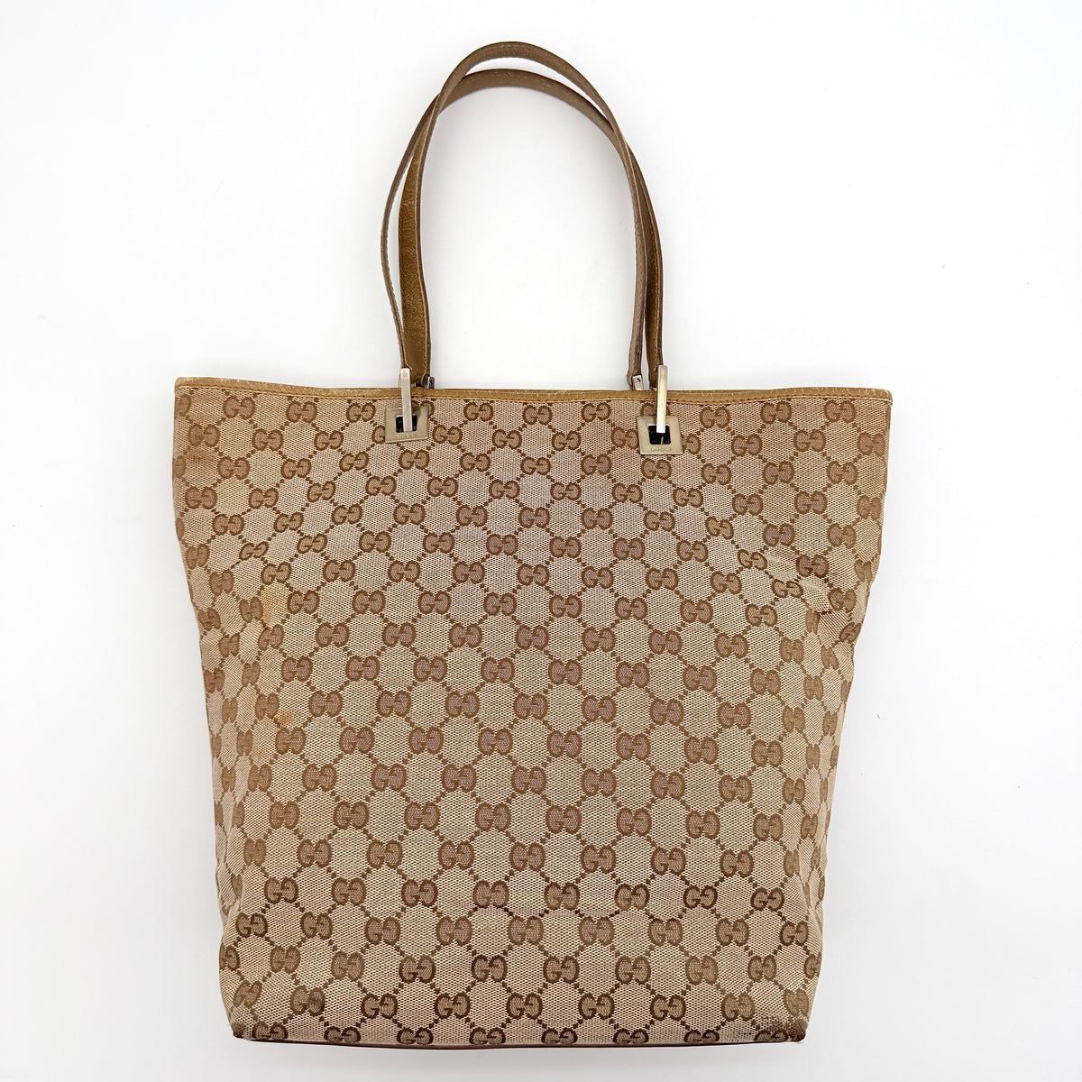 Front-facing Gucci GG Monogram Tote Bag in beige canvas with brown leather trim and double handles.