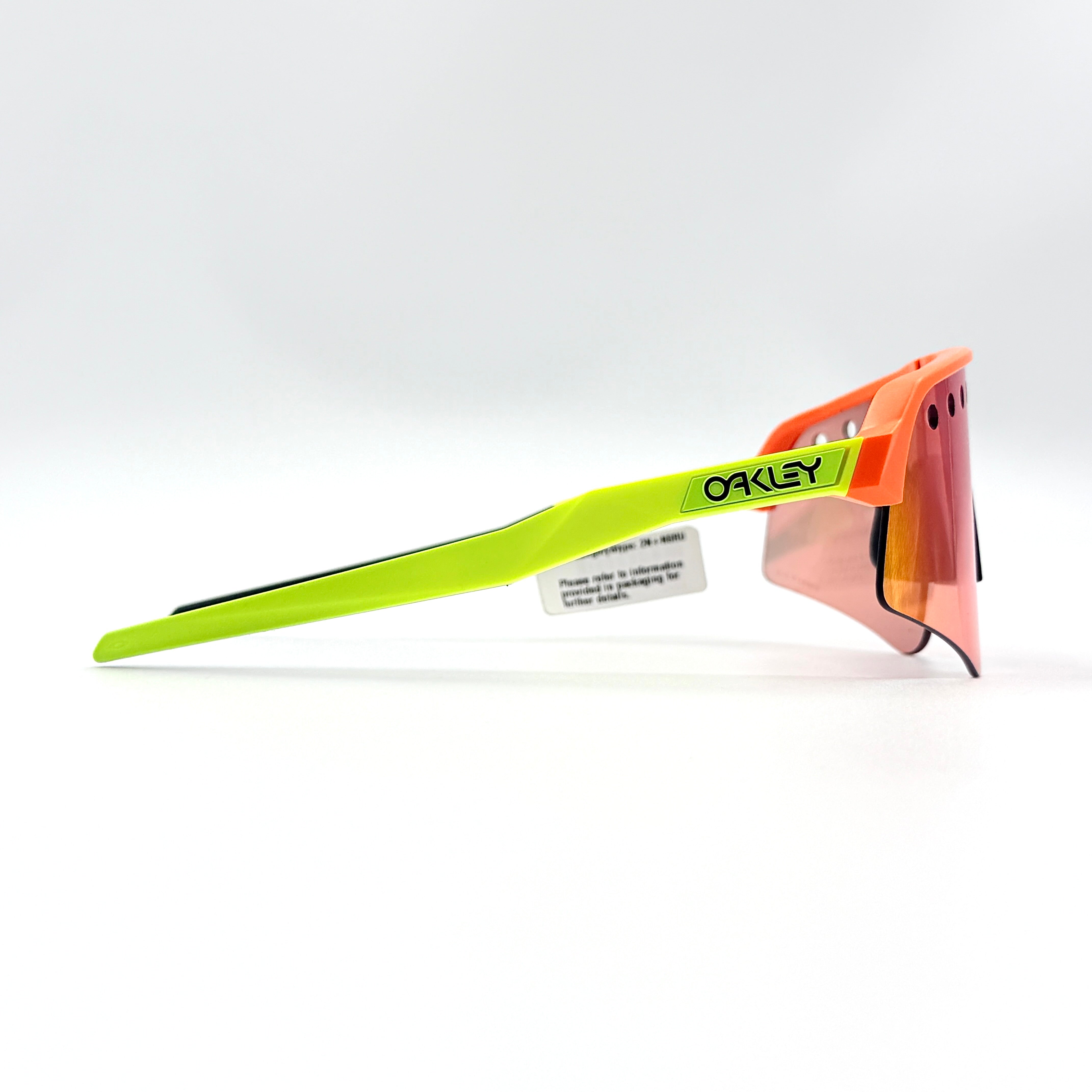 Oakley Sutro Lite Sweep sunglasses in neon yellow and orange with Prizm Trail Torch shield lens, displayed with box and case.