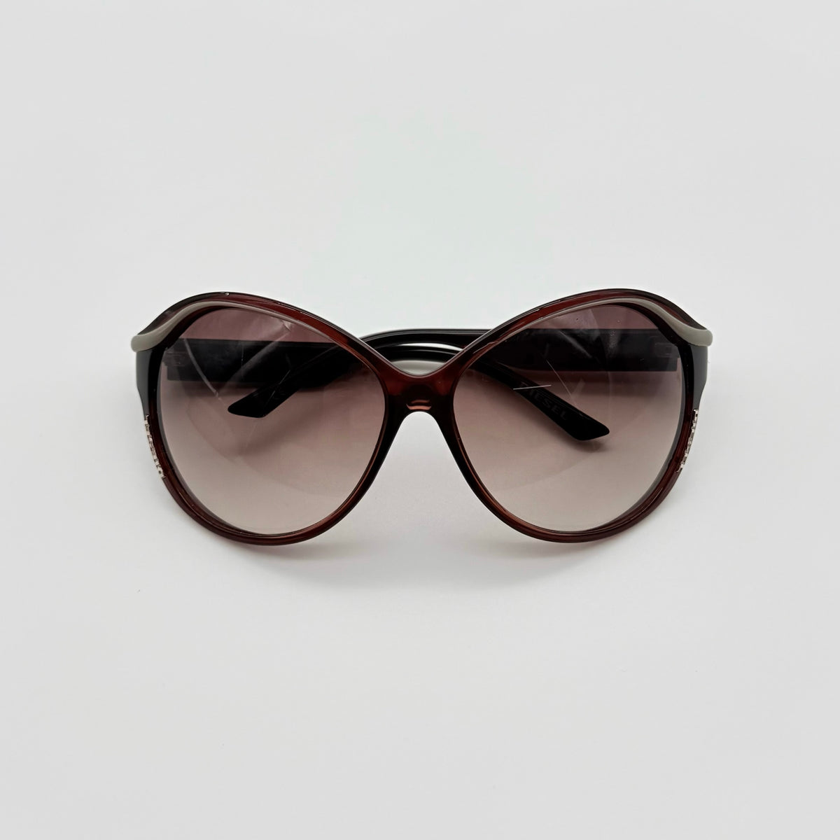 Diesel DS0094 sunglasses in gradient brown with oversized round lenses, shown with branded case and cleaning cloth.