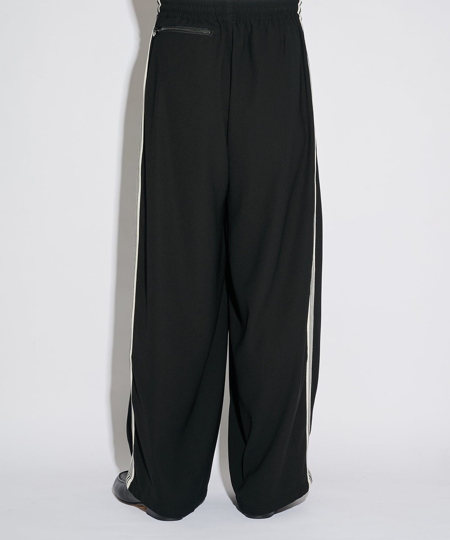 Needles H.D. Track Pant in black with white stripes and butterfly logo, shown in a full-length styled view.