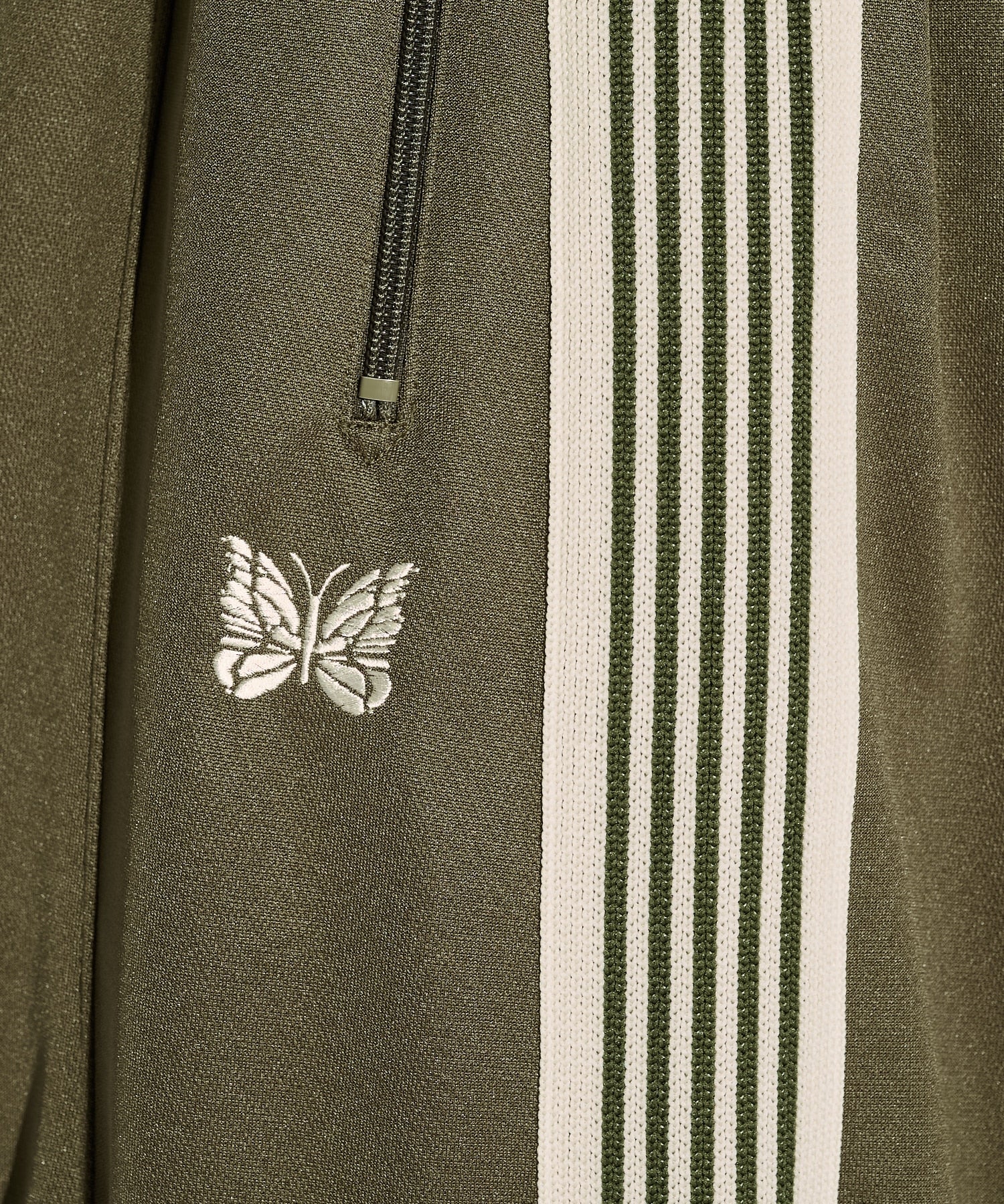 Needles H.D. Track Pant in olive green with cream stripes and butterfly logo, shown in a relaxed silhouette.