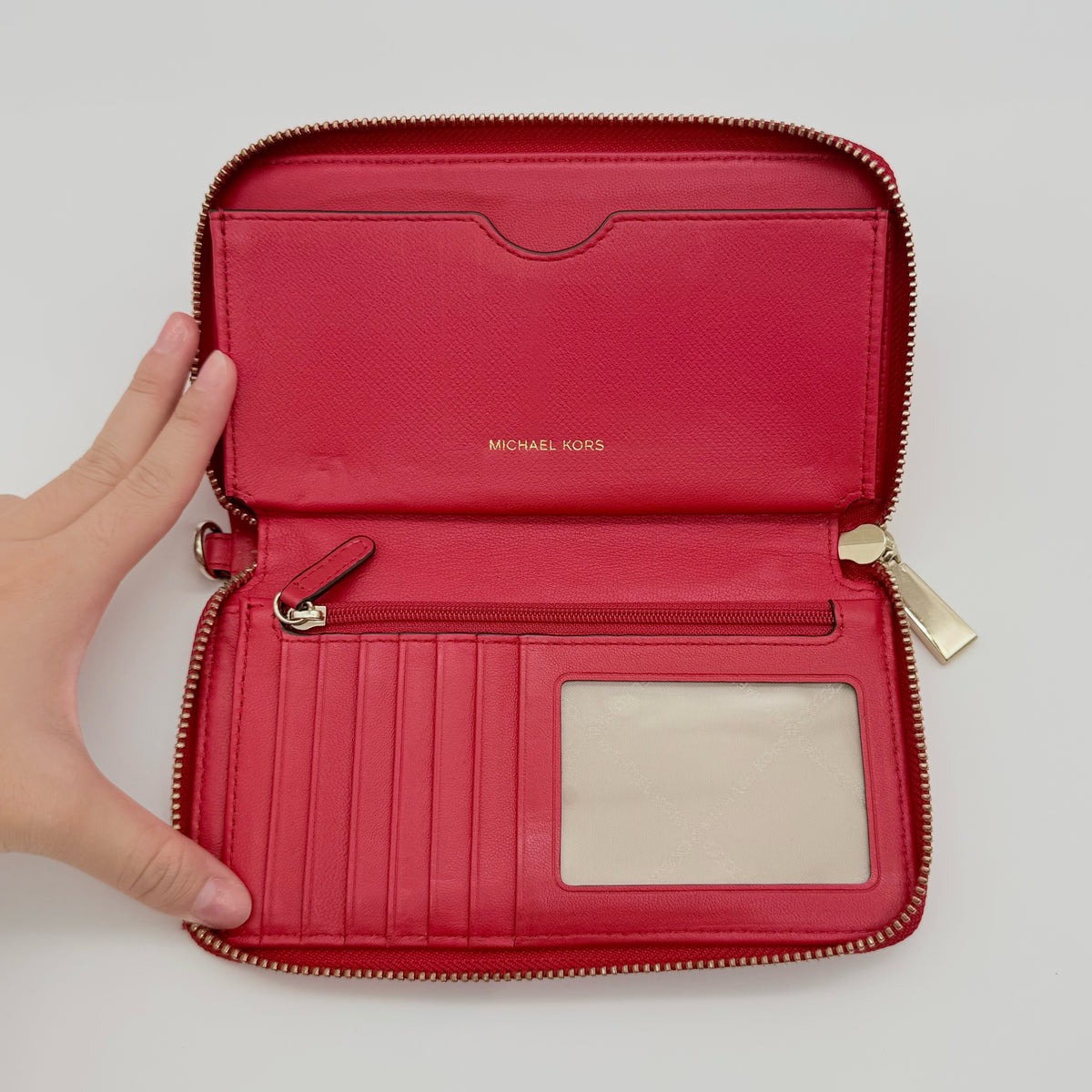 Front view of the Michael Kors red quilted large wallet with gold zip and MK monogram stitching.