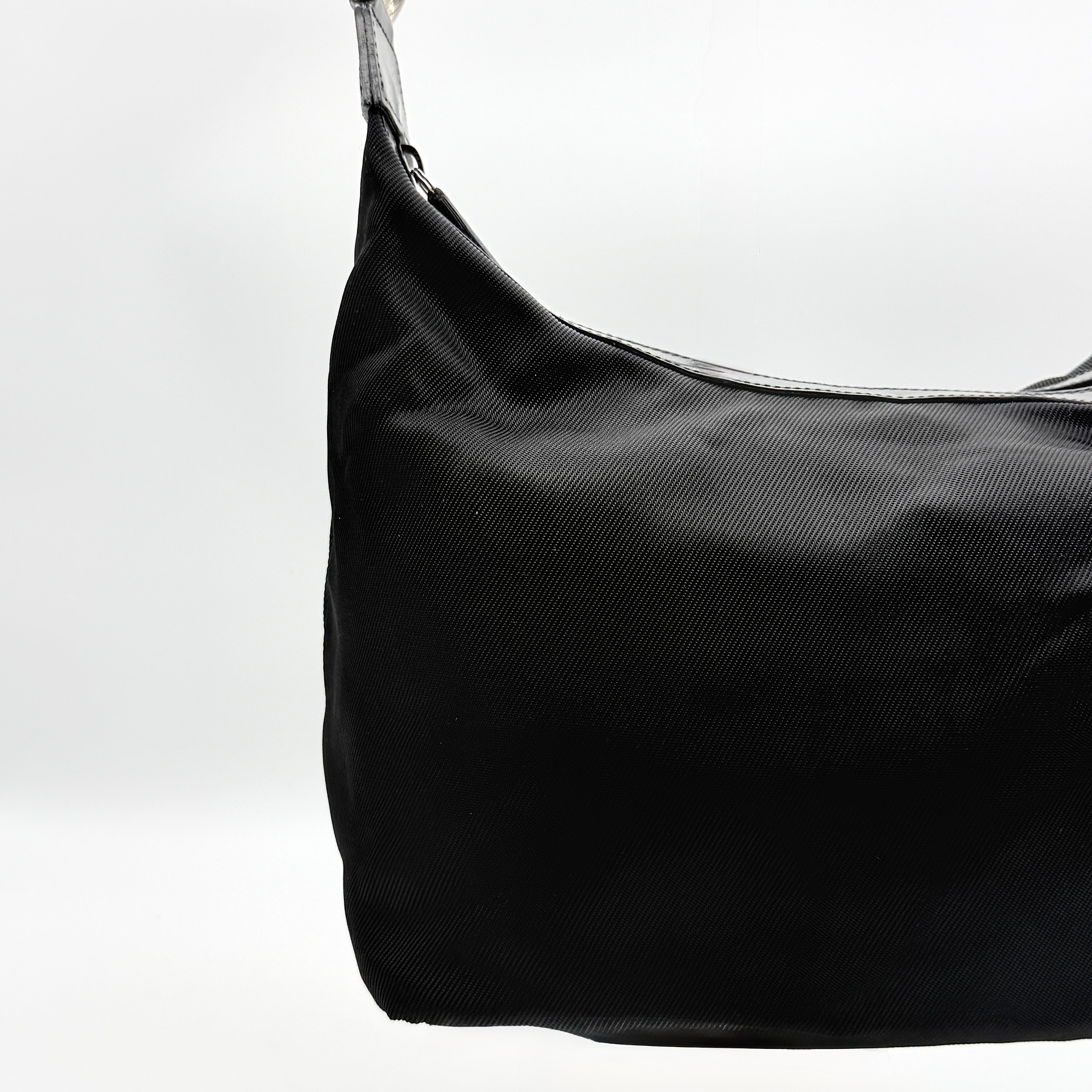 Gucci black nylon shoulder bag with bamboo handle and leather trim, photographed against a white background.