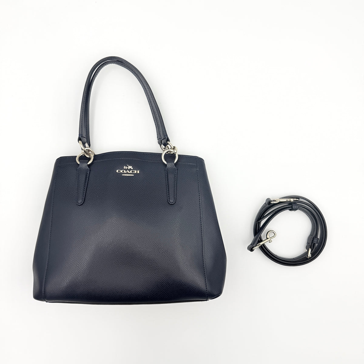 Coach Minetta Satchel in navy blue grained leather with dual handles and detachable shoulder strap displayed on a white background.