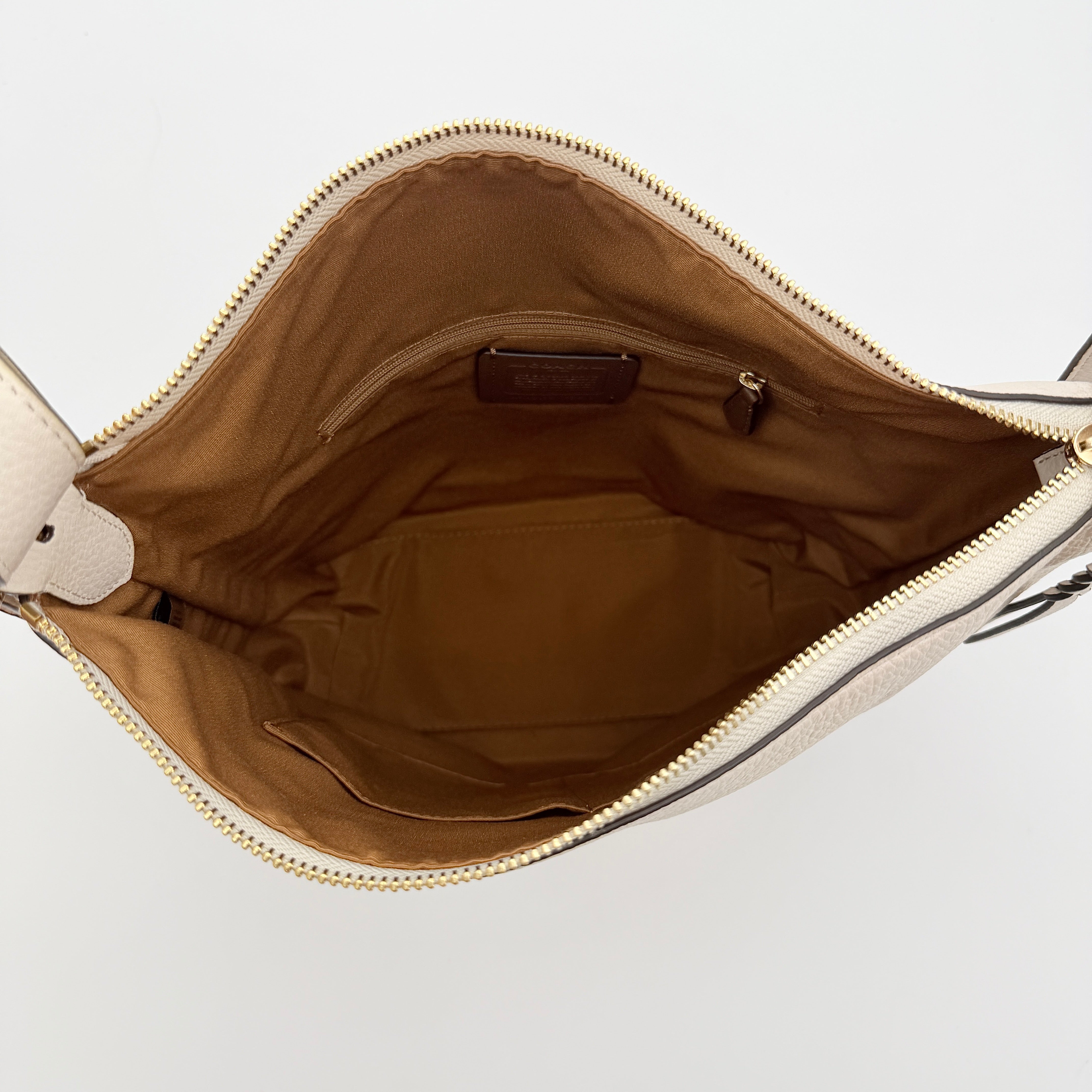 Coach Ellie File Crossbody Bag in ivory pebbled leather with gold hardware and adjustable strap, displayed on a white background.
