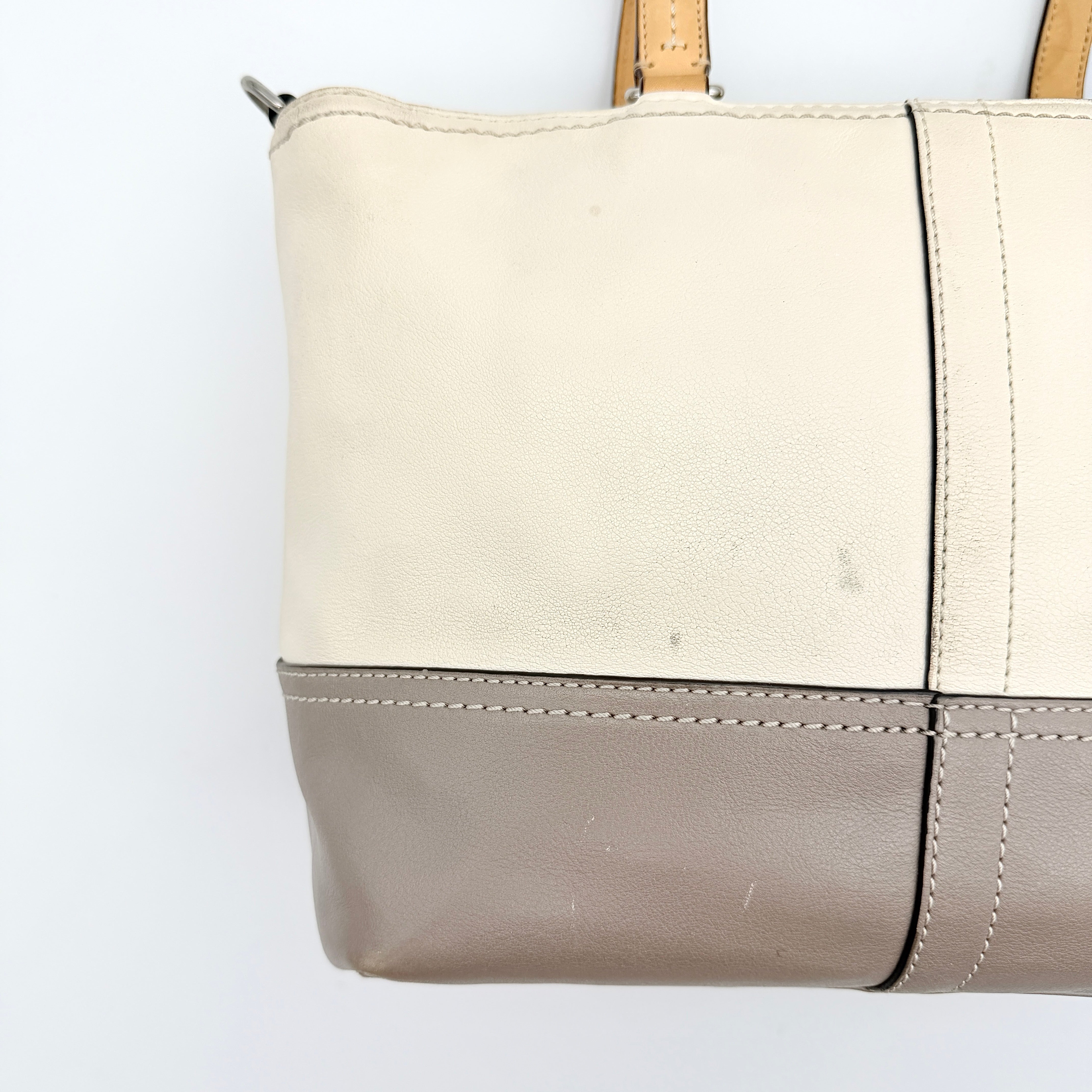 Coach Hampton Weekend perforated cream and grey leather tote bag with tan handles and a silver Coach charm, displayed against a white background.