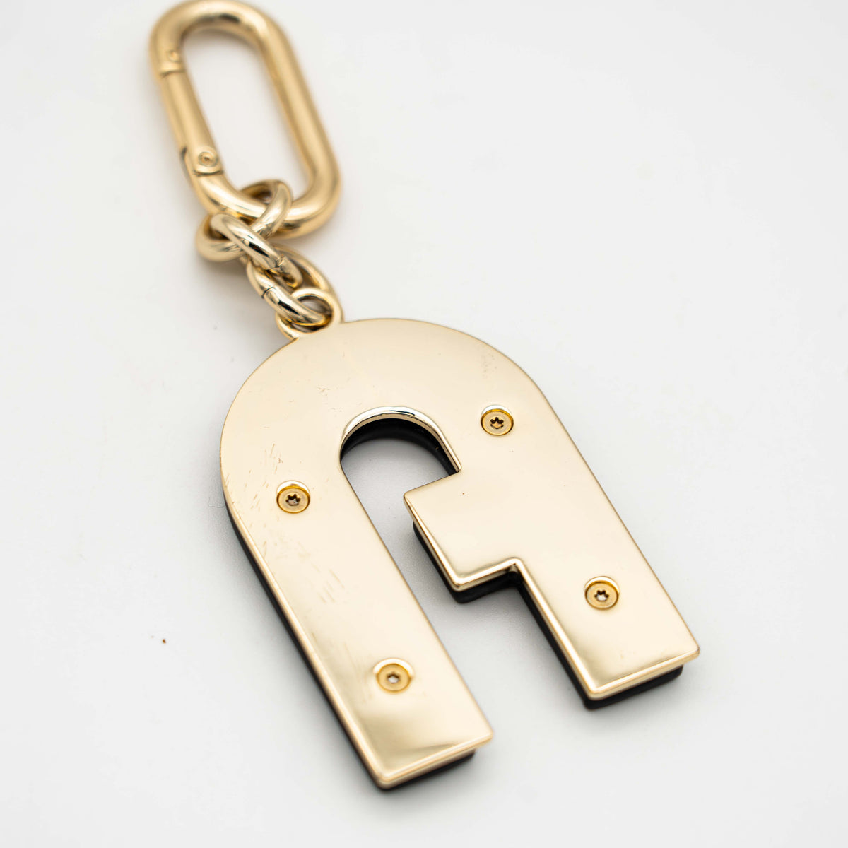 Furla Venus Arch Logo keychain in black leather with gold-tone hardware and clasp.