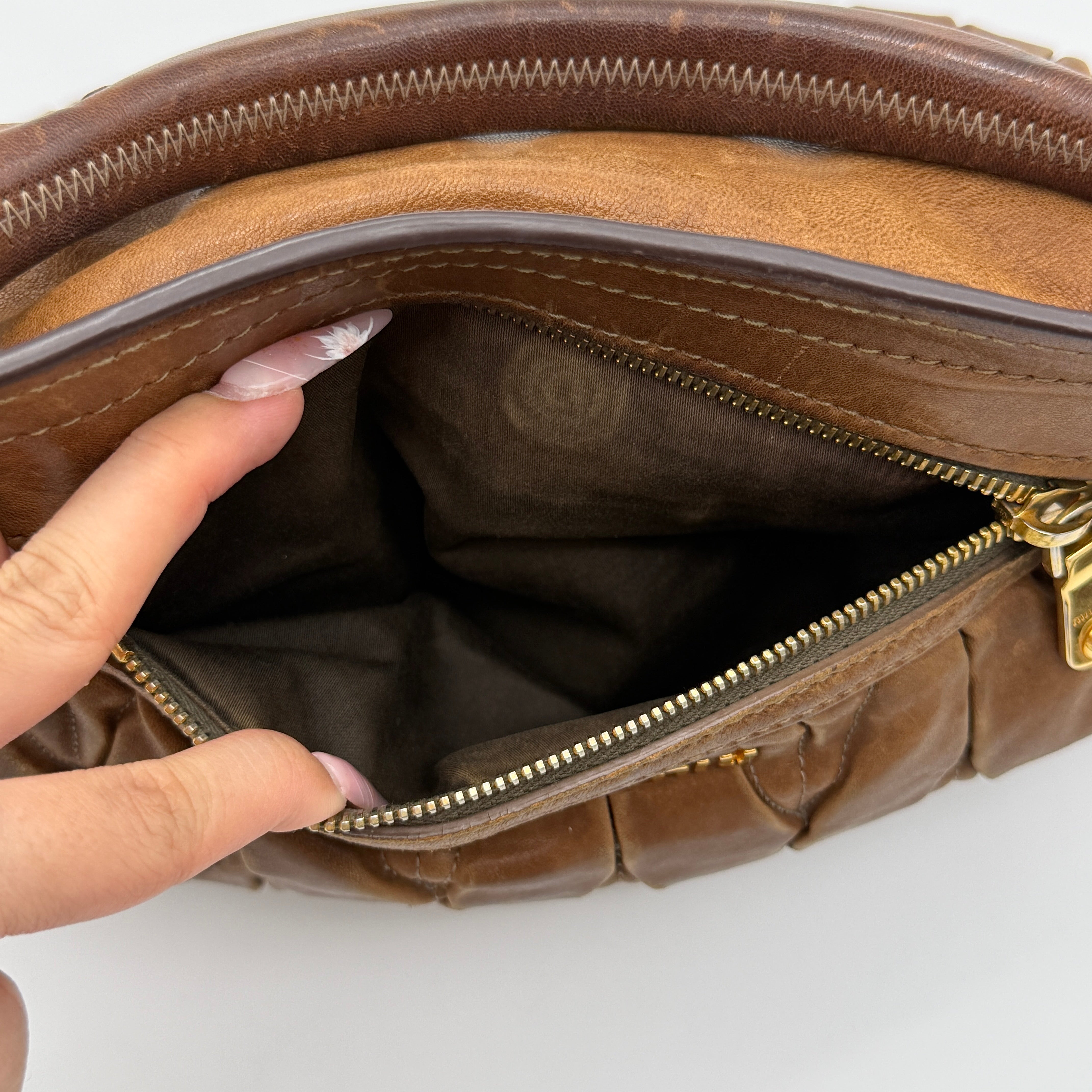 Miu Miu brown Matelasse Coffer Hobo bag with gold hardware, detachable strap, and dust bag displayed on a flat surface.