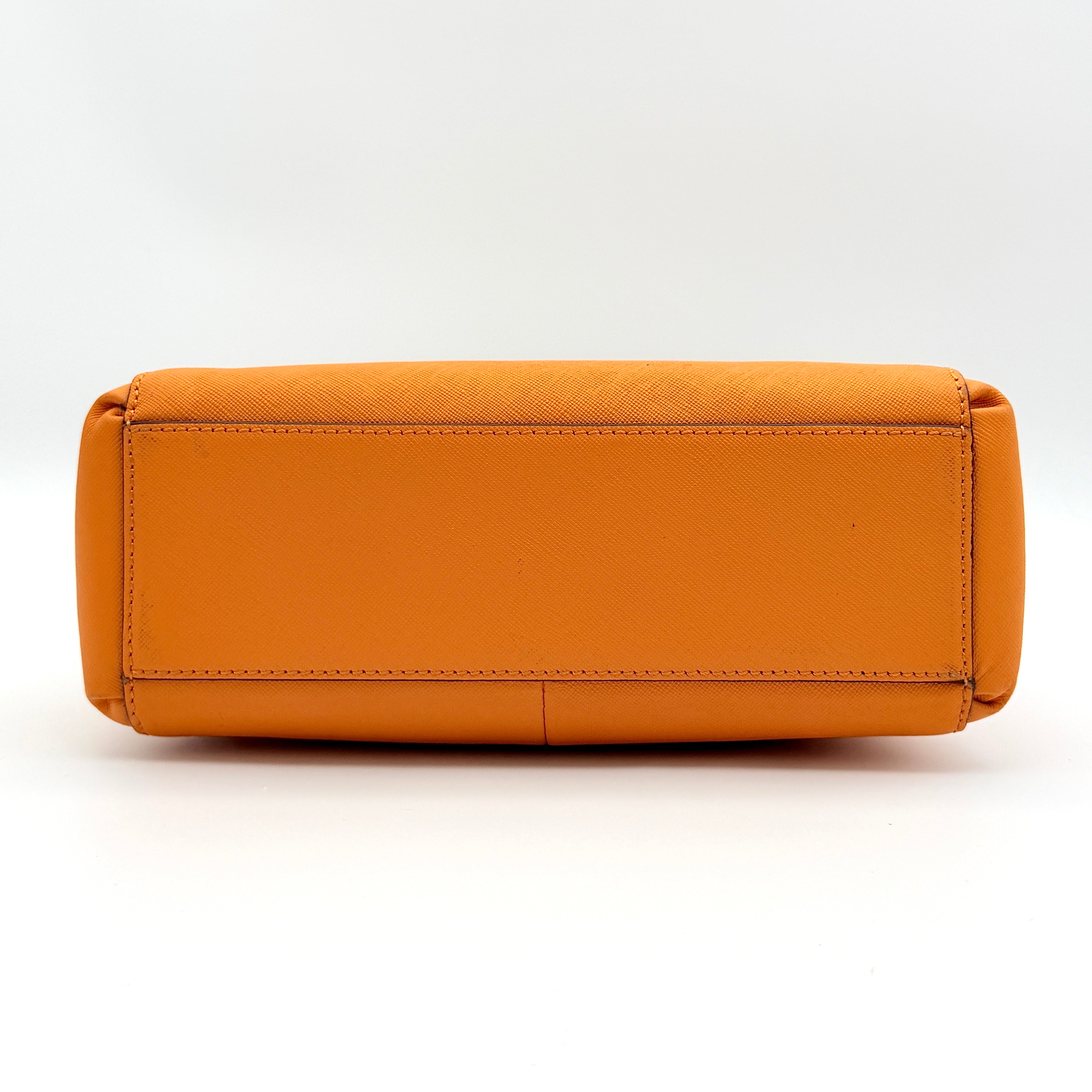 Coach Christie Carryall handbag in orange leather with gold hardware and structured handles, photographed on a white background.
