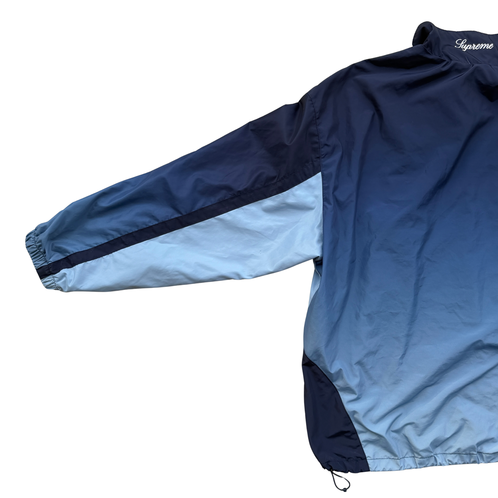 Supreme x Umbro blue gradient track jacket with white Supreme Champions lettering and crest, shown zipped with elastic cuffs and hem.