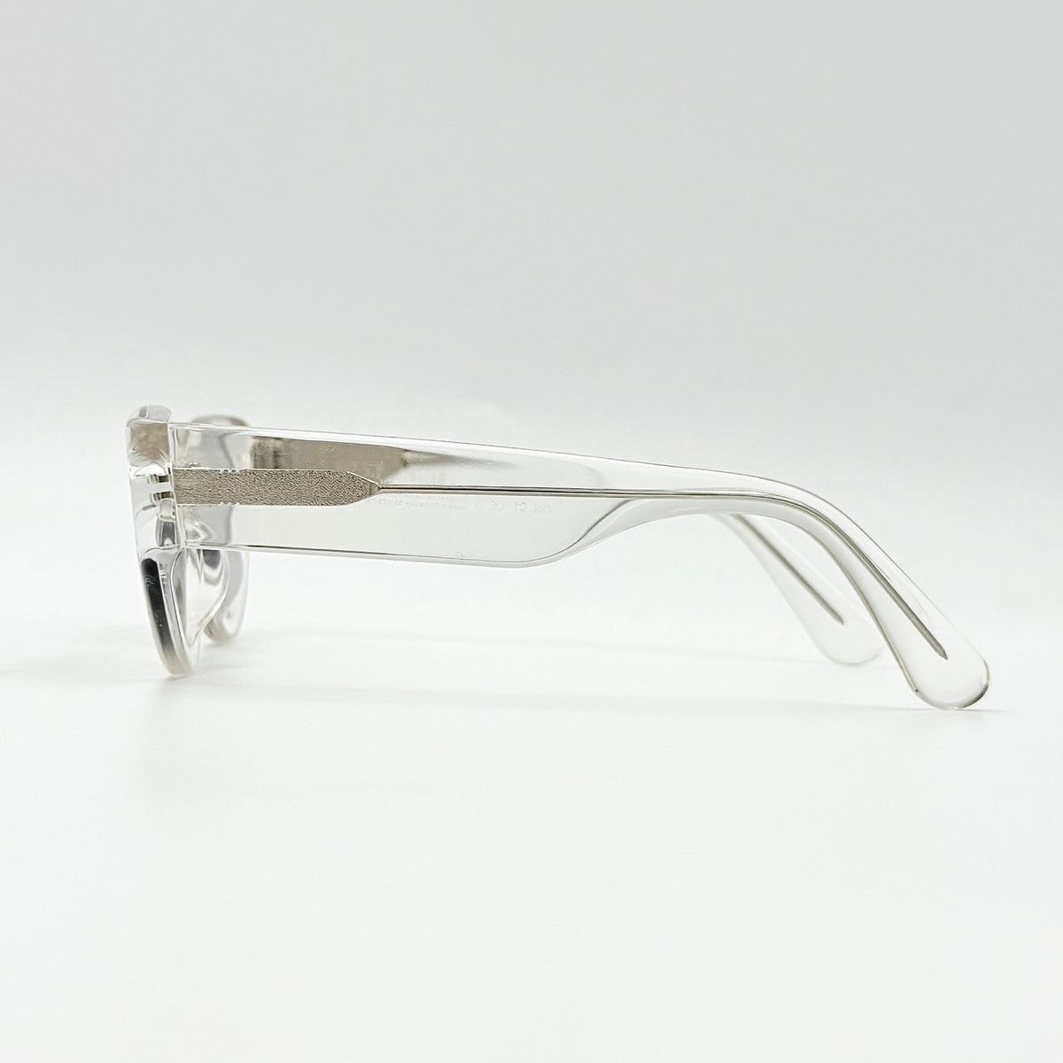 Gentle Monster Tazi transparent sunglasses with grey lenses and clear acetate frame, softly styled alongside the branded case.