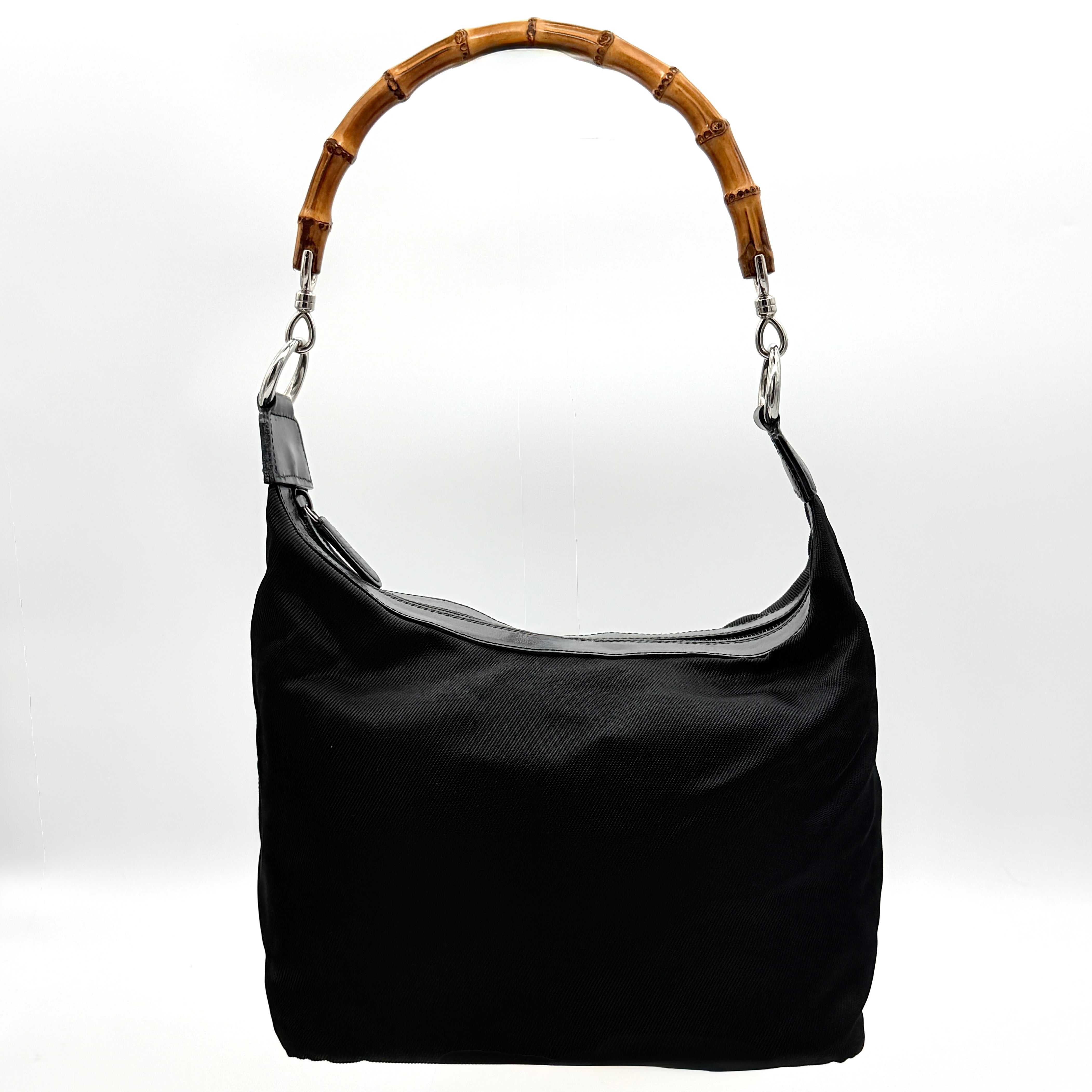 Gucci black nylon shoulder bag with bamboo handle and leather trim, photographed against a white background.
