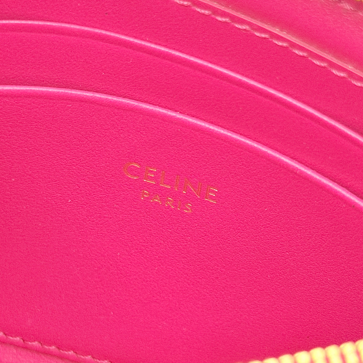 Celine quilted pink coin and card wallet with gold C charm, displayed on a black Celine dust bag.
