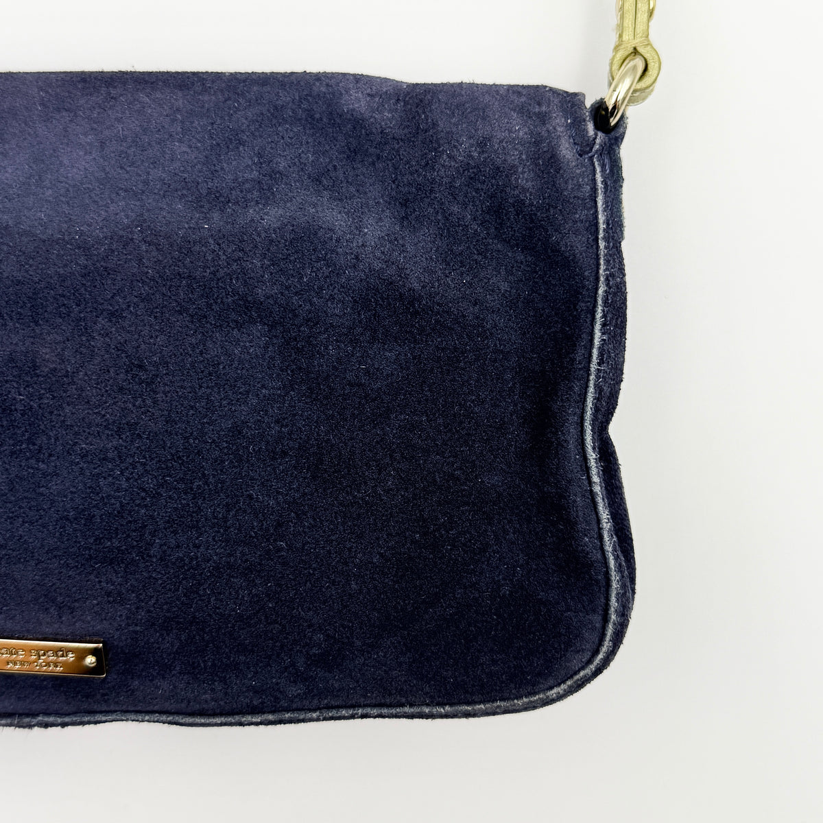Navy blue suede Kate Spade baguette bag with floral gold hardware and gold-tone shoulder strap.