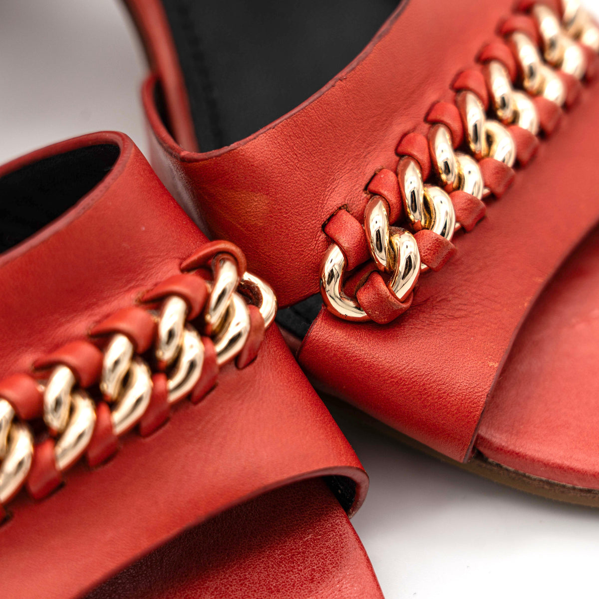 Coach Phoebe block heels in red leather with gold chain detailing, displayed with chunky wood-stacked heels and adjustable ankle straps.