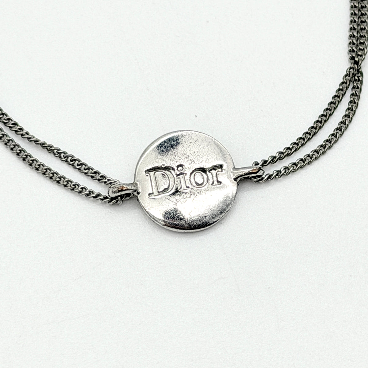 Christian Dior silver double chain bracelet with Dior logo medallion and adjustable clasp.