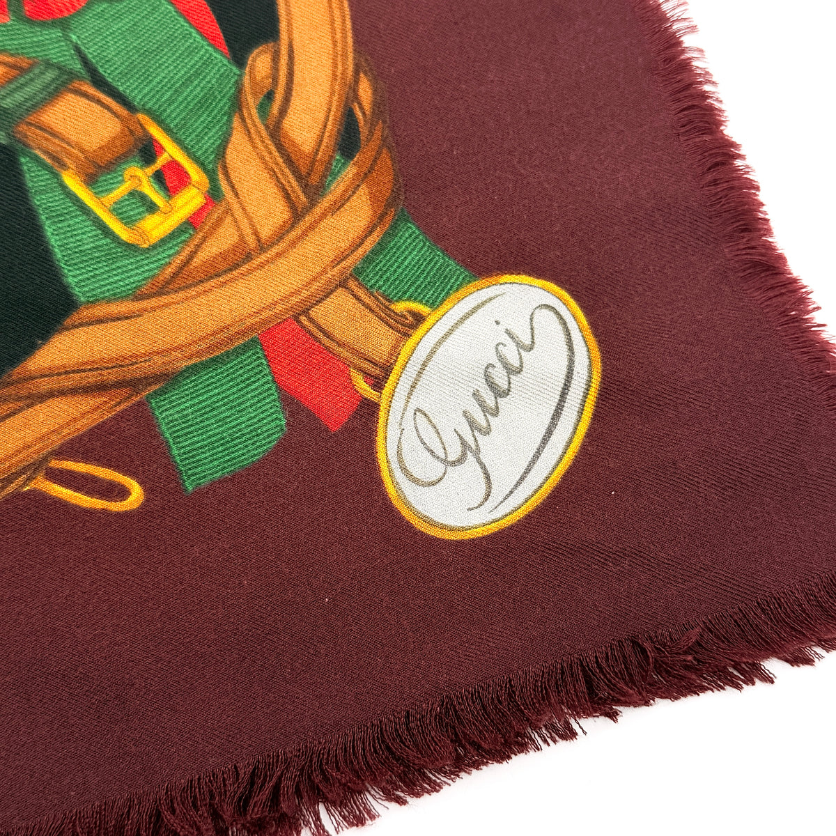 Gucci equestrian tartan shawl scarf in burgundy with heritage motifs and a fringed edge, styled folded.