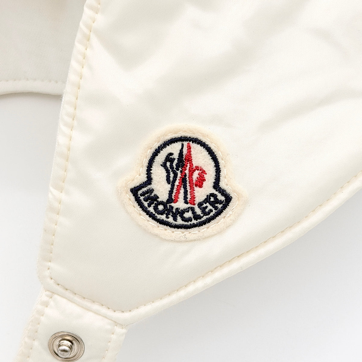 Moncler ivory quilted trapper hat with plush faux fur trim and signature logo patch displayed on white background.