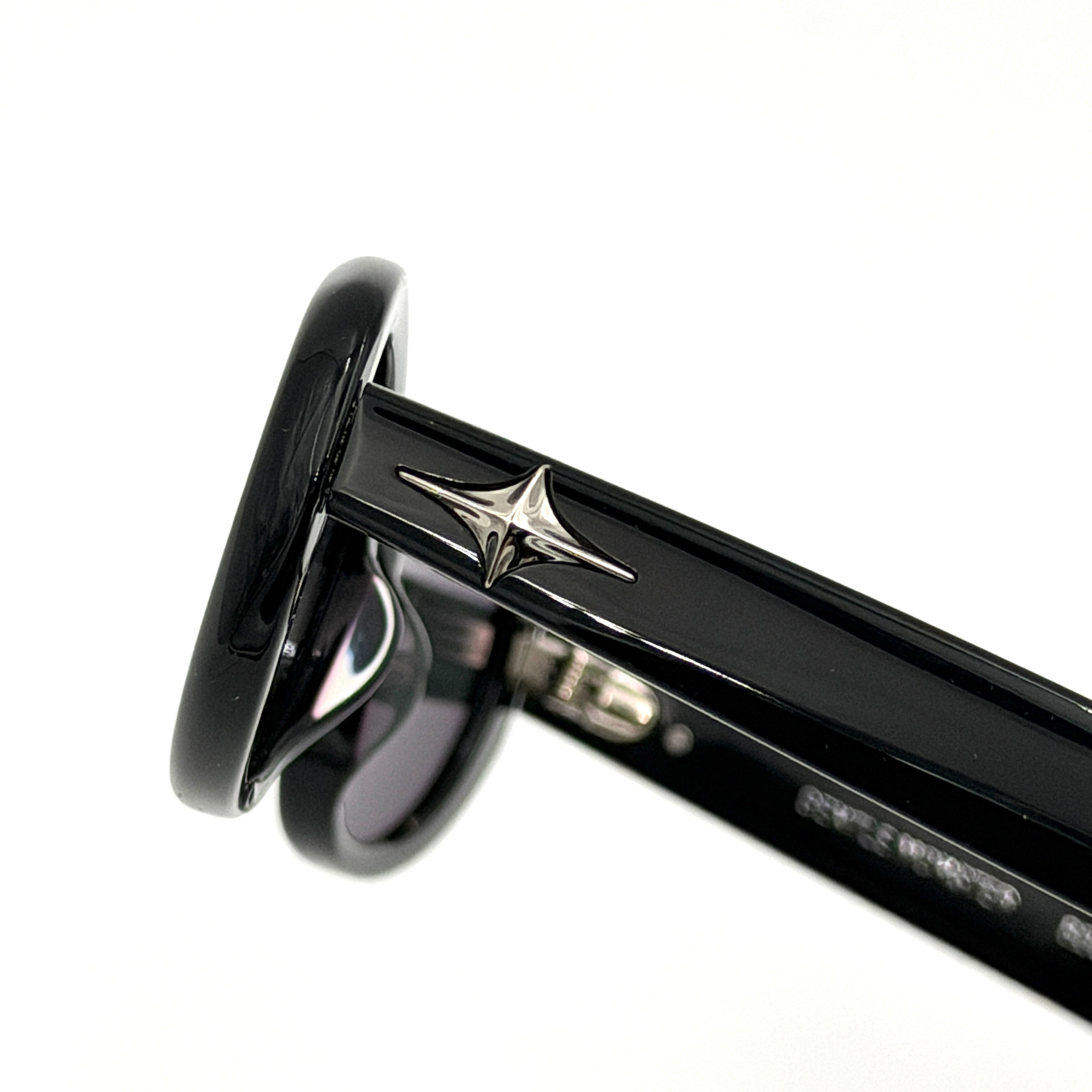 Gentle Monster Bandoneon.S sunglasses in black acetate with dark oval lenses and silver star accents shown from the side.