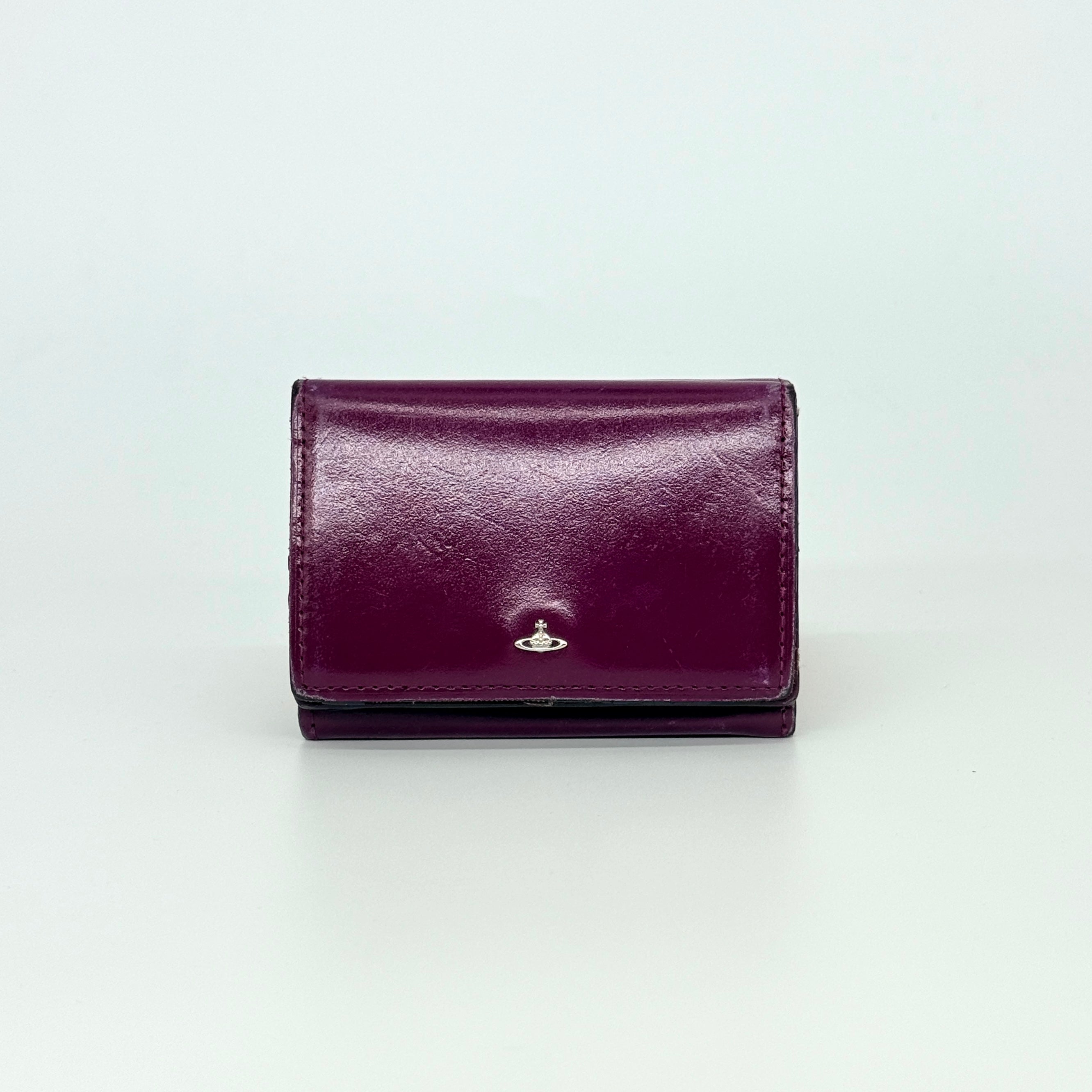 Vivienne Westwood Signature Orb Wallet in glossy purple leather with silver orb emblem on the front flap.