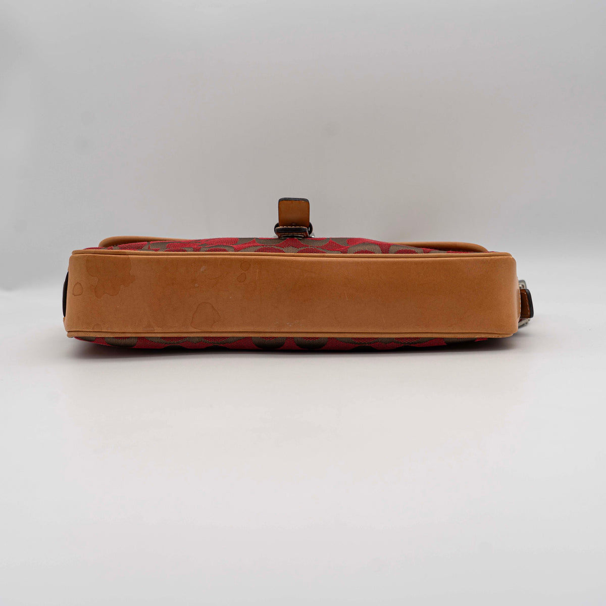 Coach Signature Soho Buckle Baguette in red and tan canvas with leather trim and a silver buckle, shown on a white background.