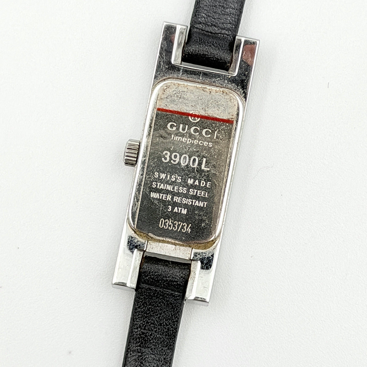Gucci 3900L black dial watch with silver-tone rectangular case and black leather strap displayed on a stand