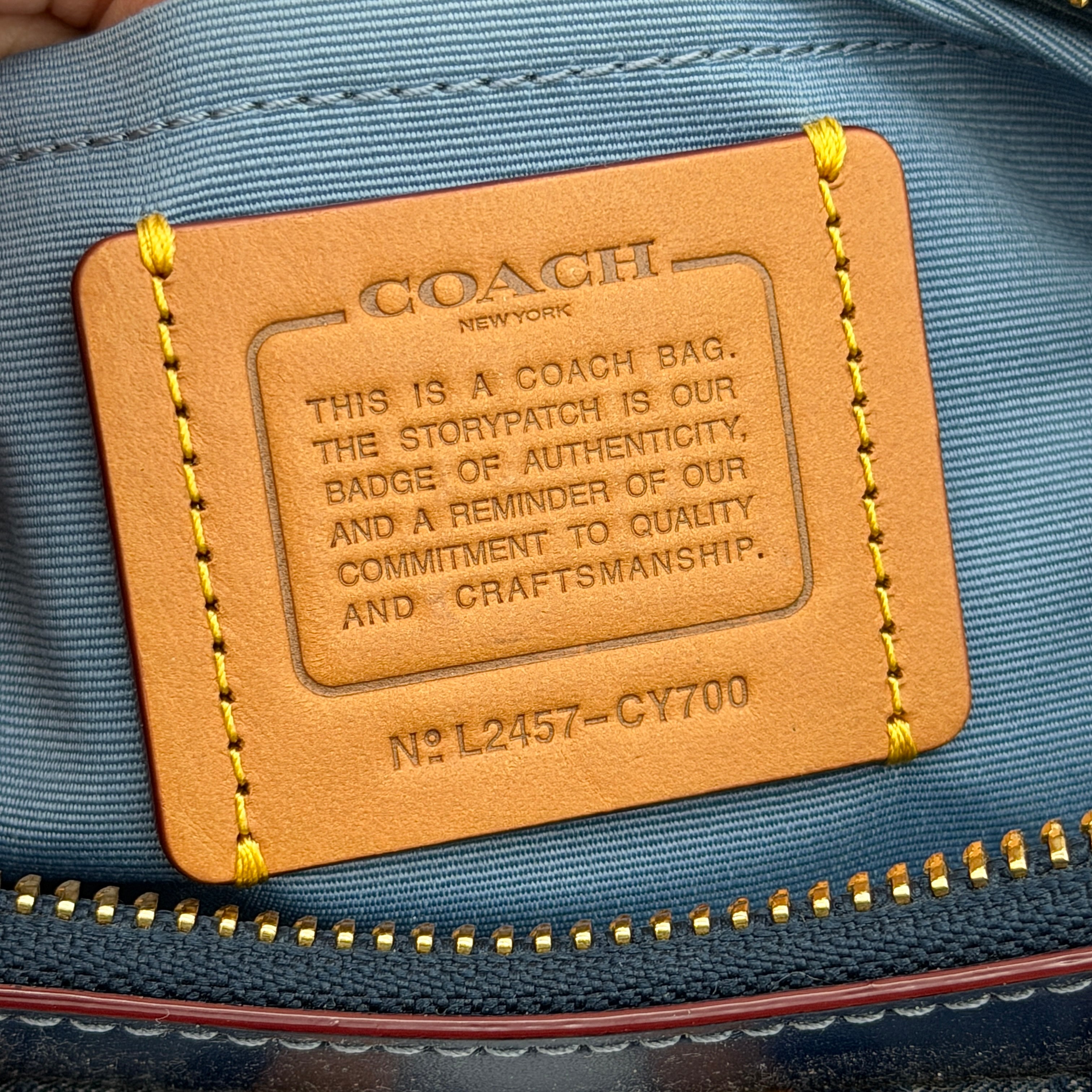 Coach Signature Ashton shoulder bag in blue denim and tan leather with gold hardware, shown with removable strap and dust bag.