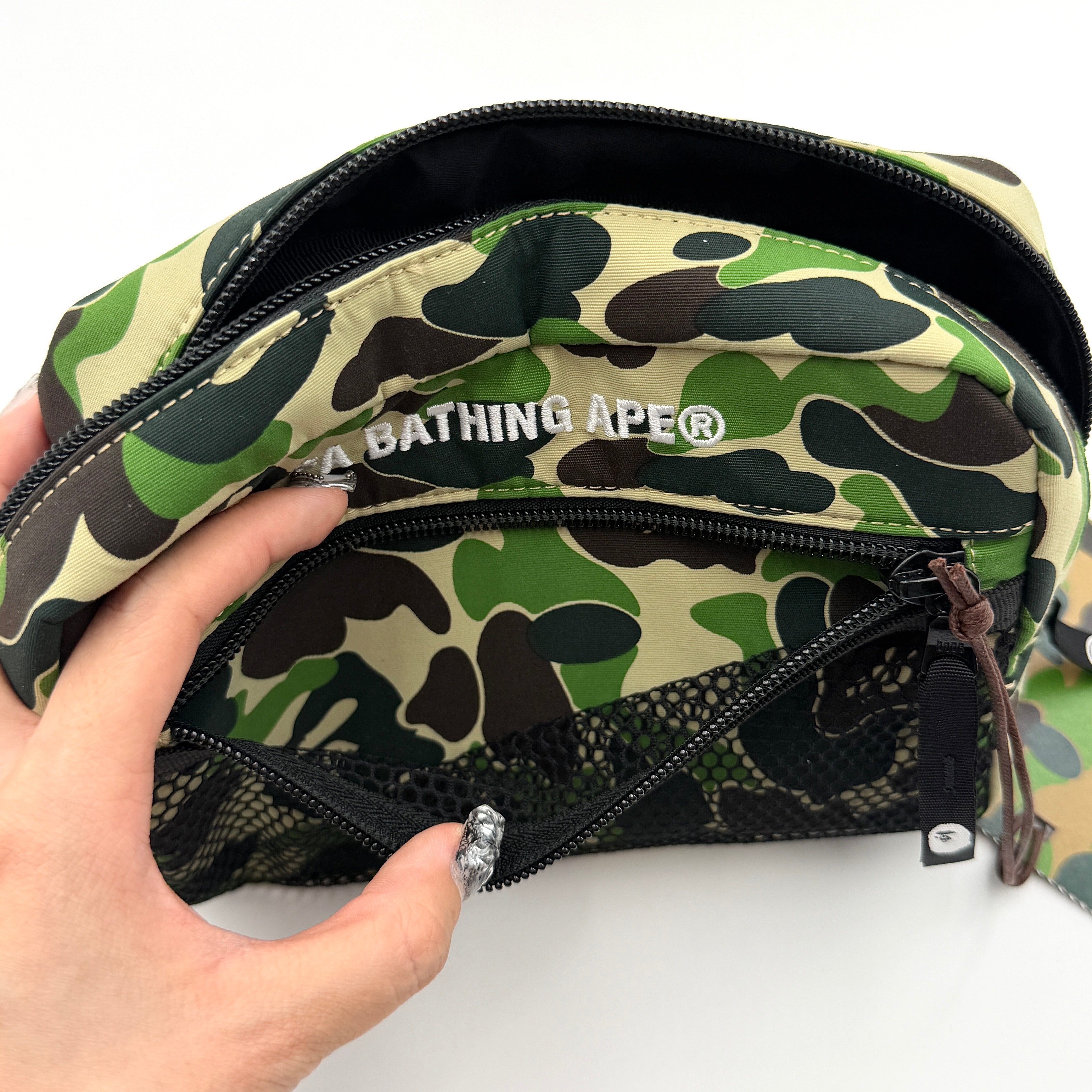 BAPE ABC Camo Pouch in green camouflage with mesh front pocket and embroidered A Bathing Ape logo.